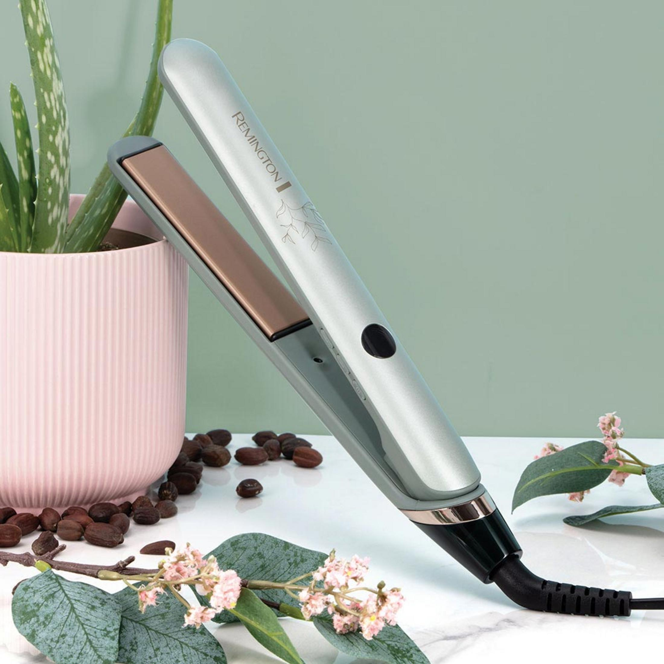 Ein Remington Glätteisen mit kupferfarbenen Platten neben einer Aloe Vera Pflanze und Blüten.