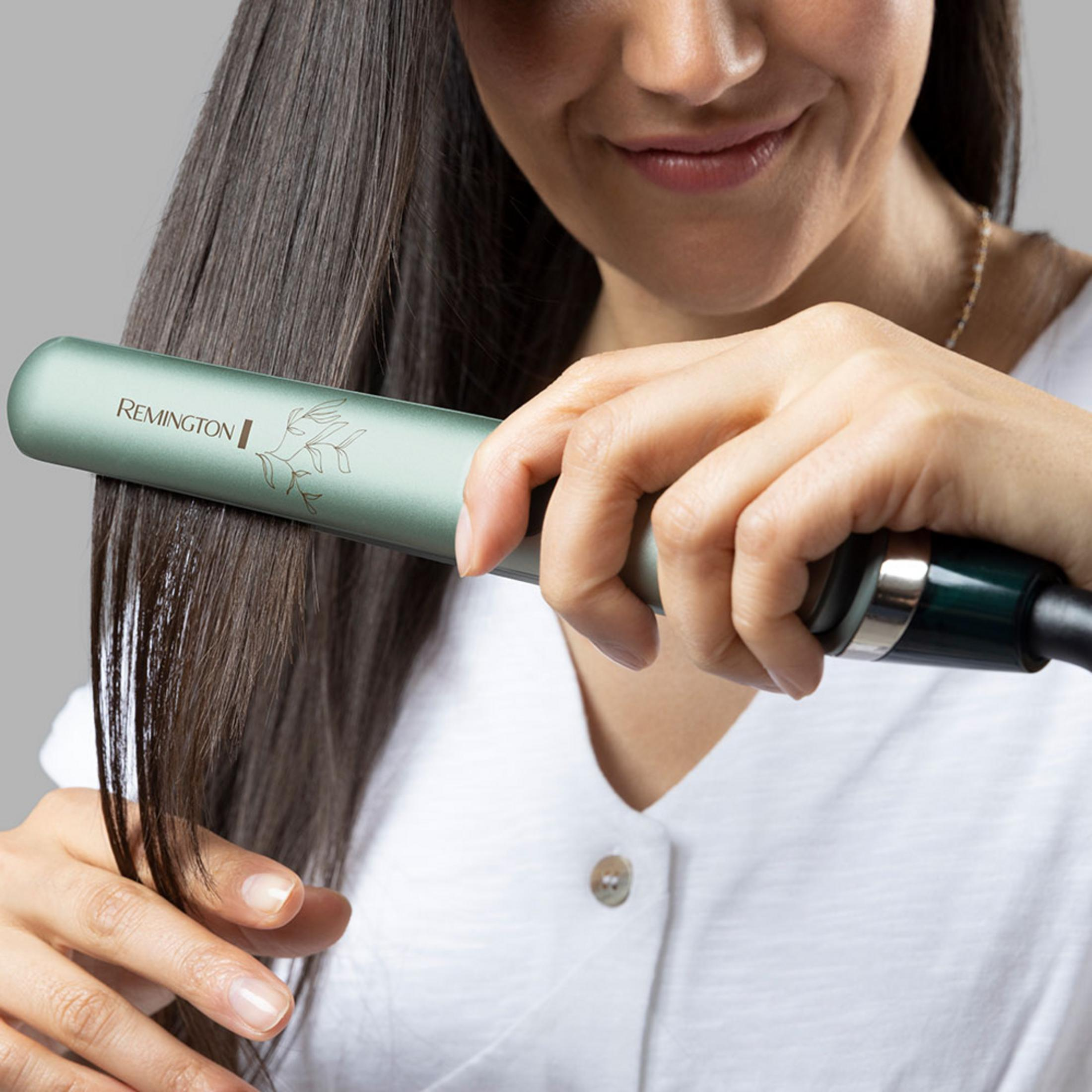 Eine Frau glättet ihr dunkles Haar mit einem grünen Remington Glätteisen.