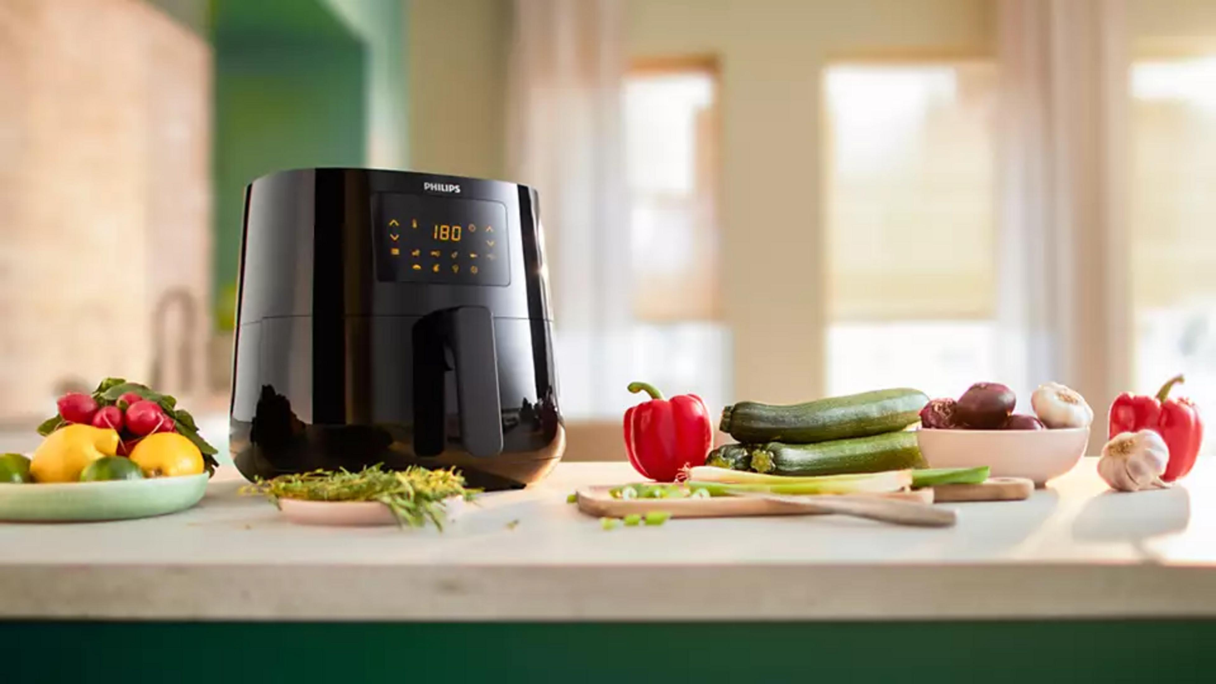 Zwarte Philips Airfryer met groenten en citrusvruchten op een aanrecht.