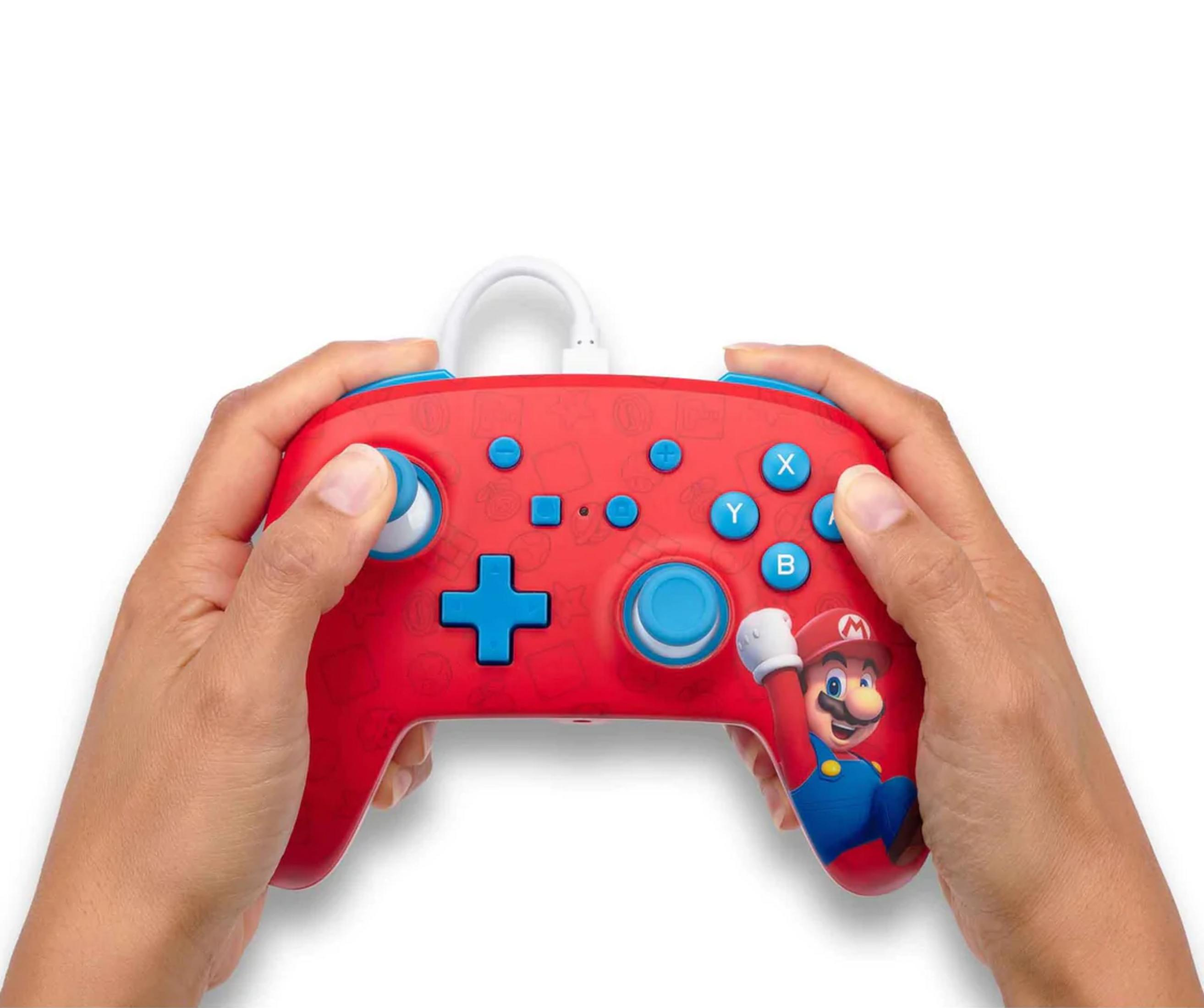 Dłonie trzymające czerwony kontroler do gier z Mario i niebieskimi przyciskami.