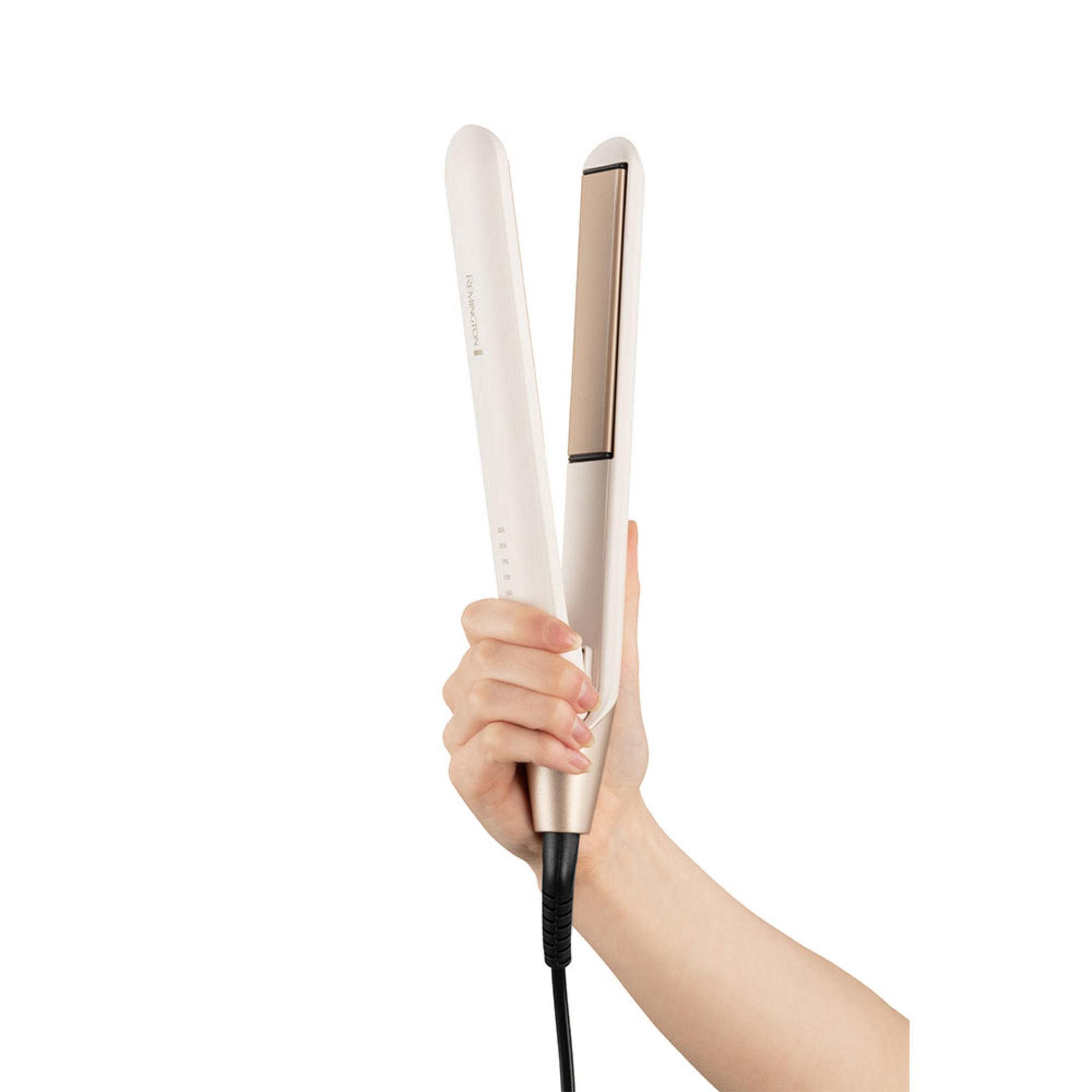 Eine Hand hält einen weißen Remington Glätteisen mit goldenen Platten.