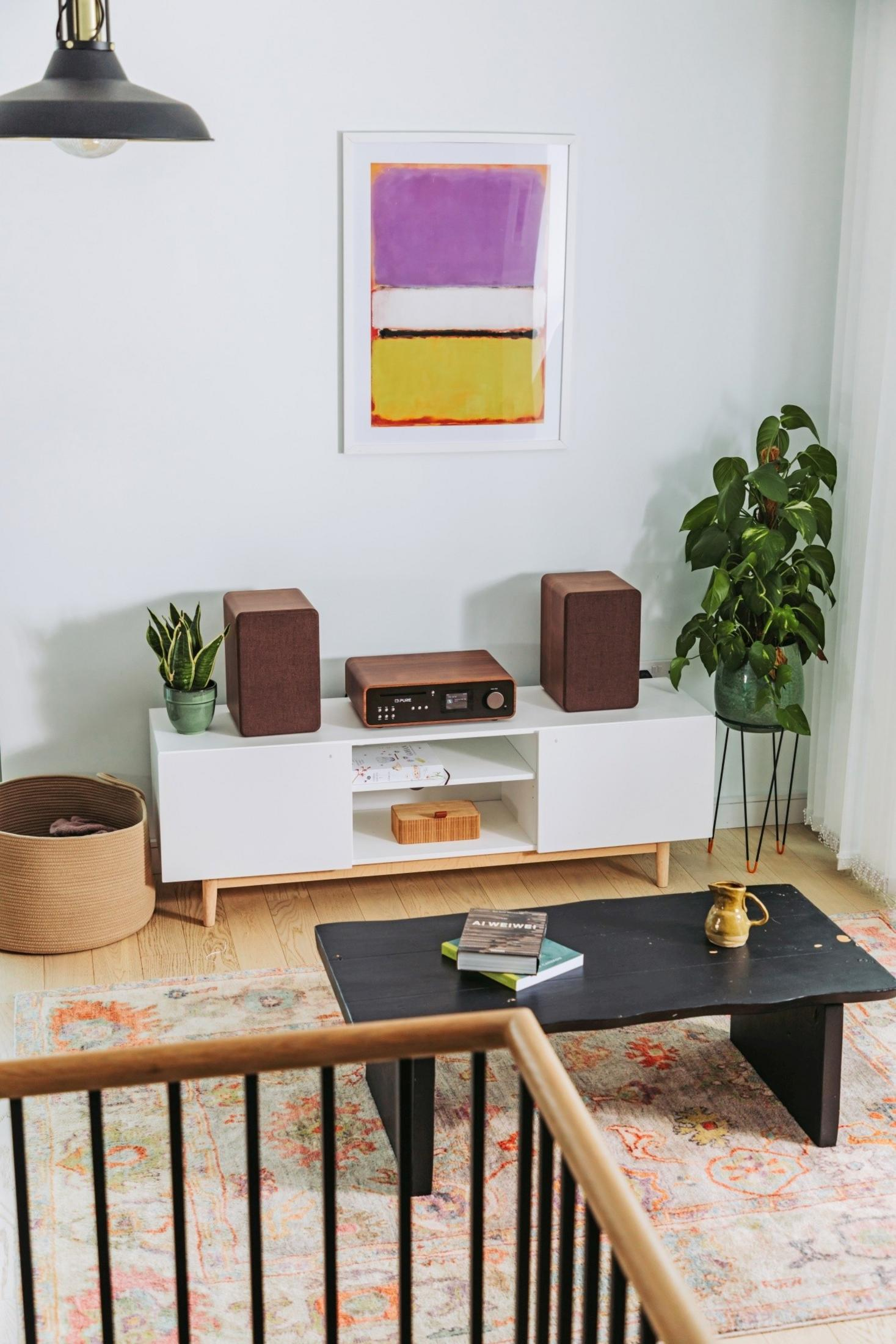 Ein Wohnzimmer mit weißem Sideboard, braunen Lautsprechern, einem Plattenspieler und einem Bild.