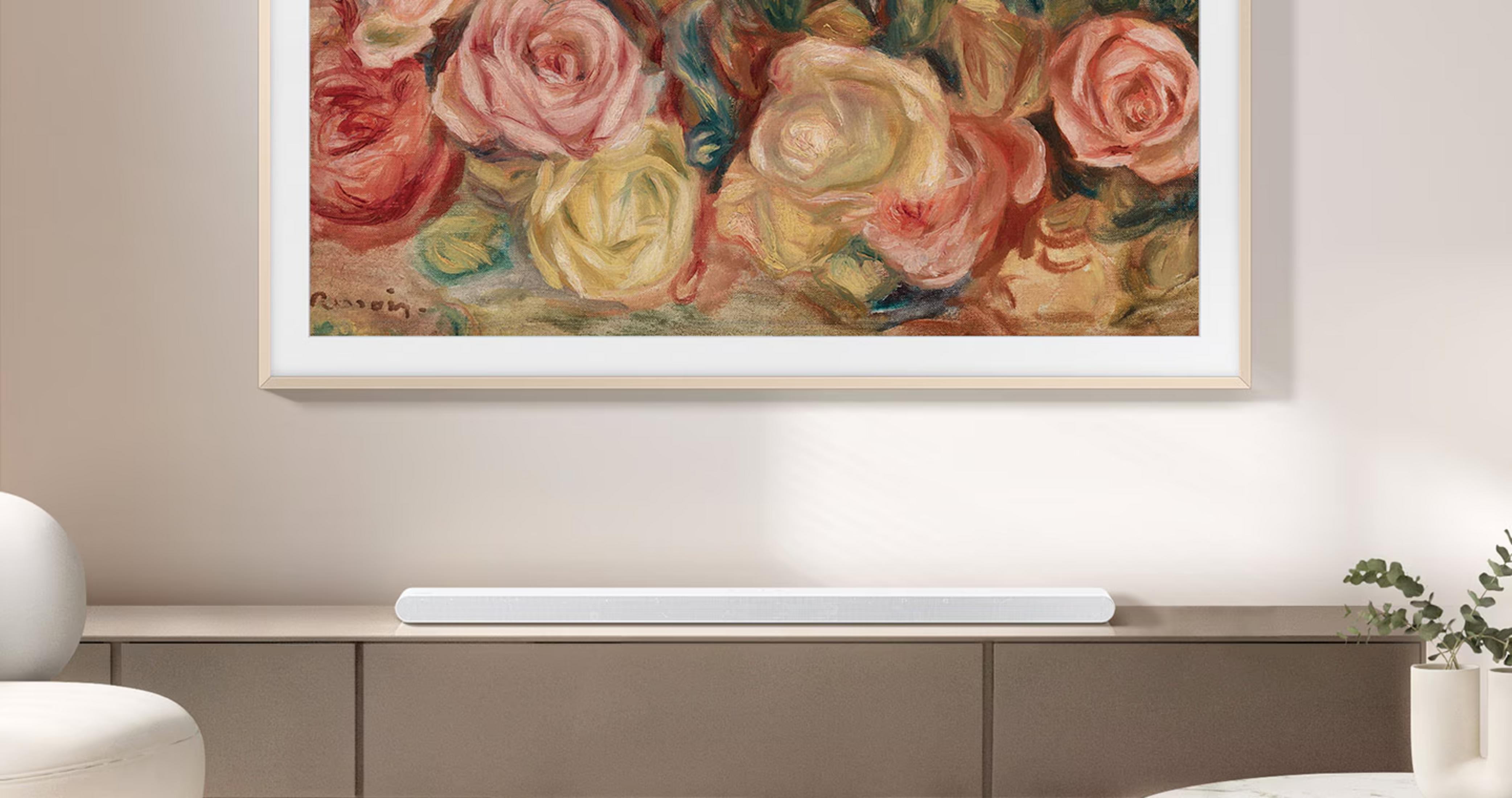 Une barre de son blanche repose sur un meuble marron sous un tableau floral.