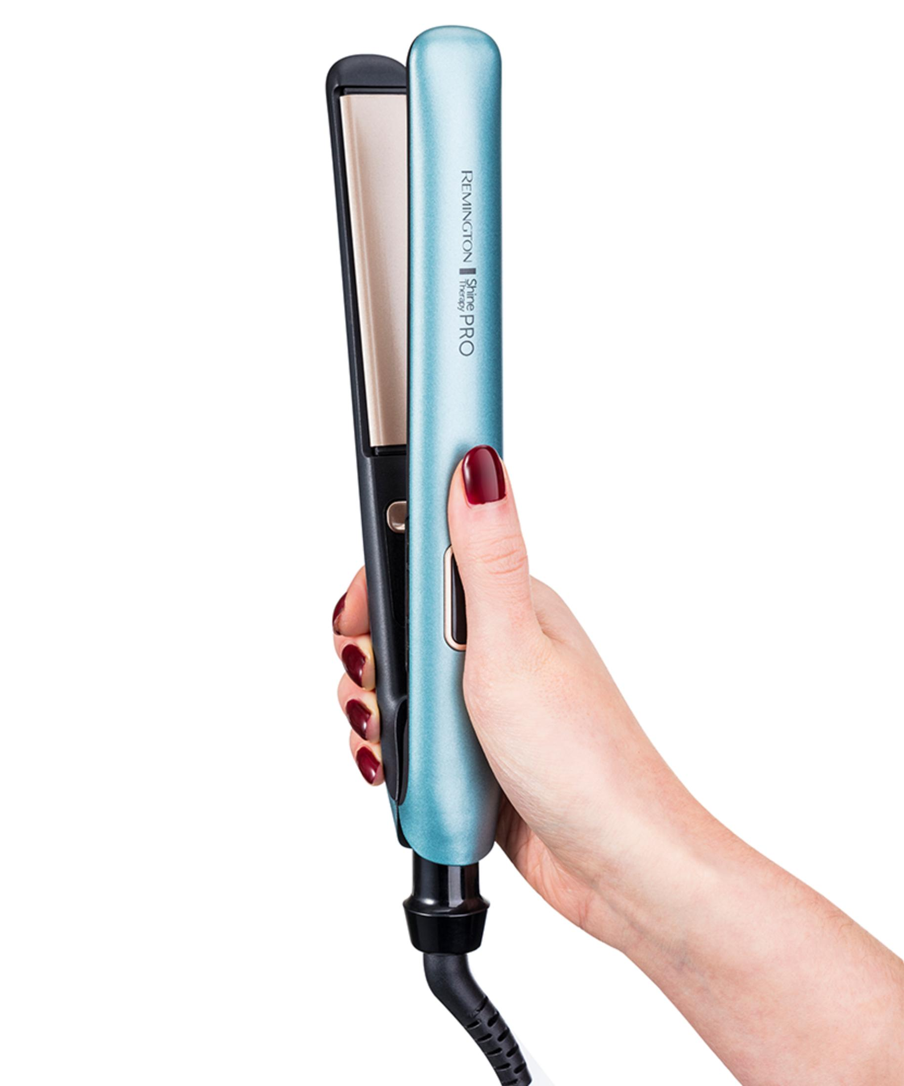 Dłoń z ciemnoczerwonymi paznokciami trzyma niebieską prostownicę Remington.