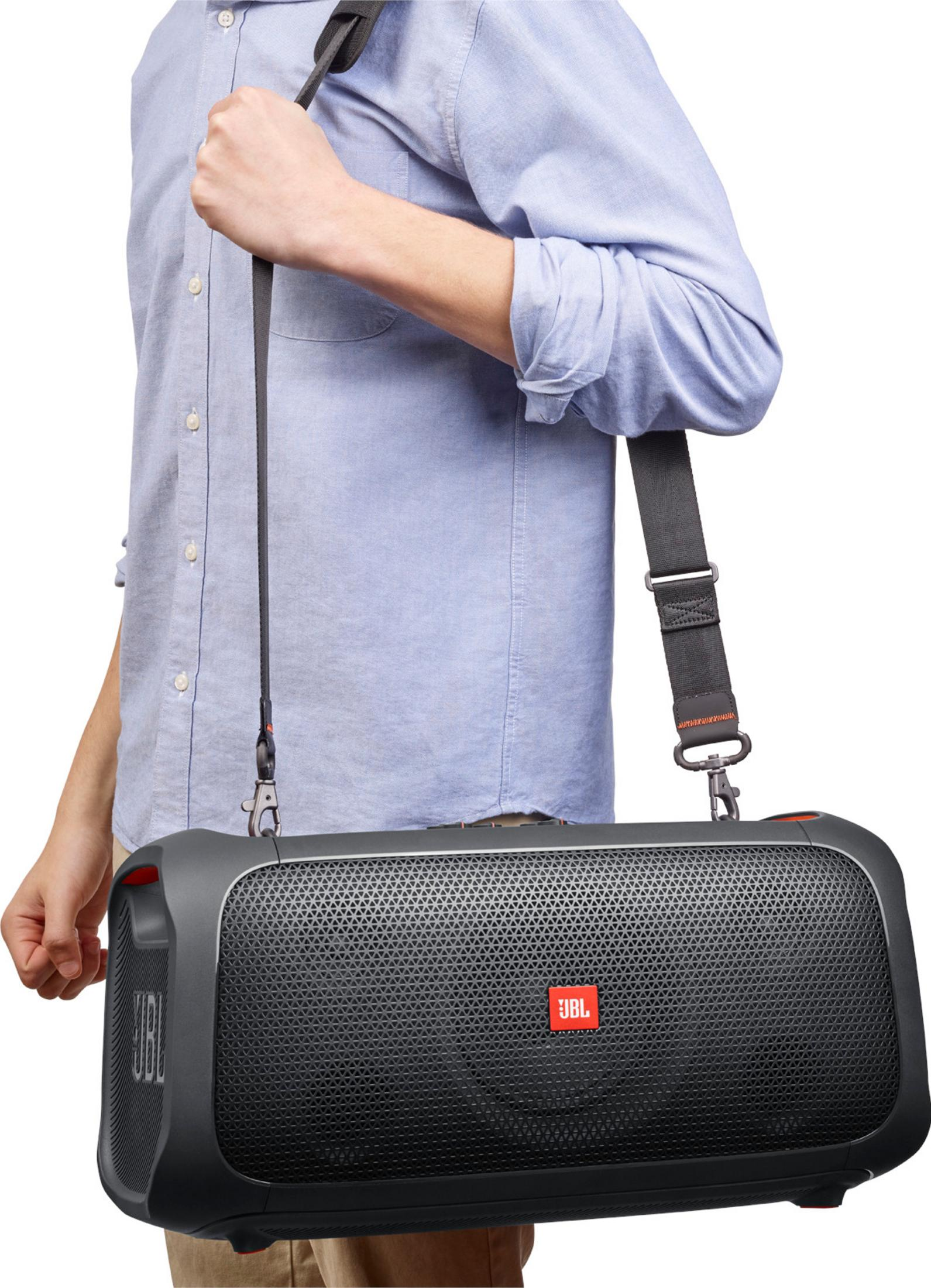 Hombre llevando un altavoz JBL negro sobre el hombro.