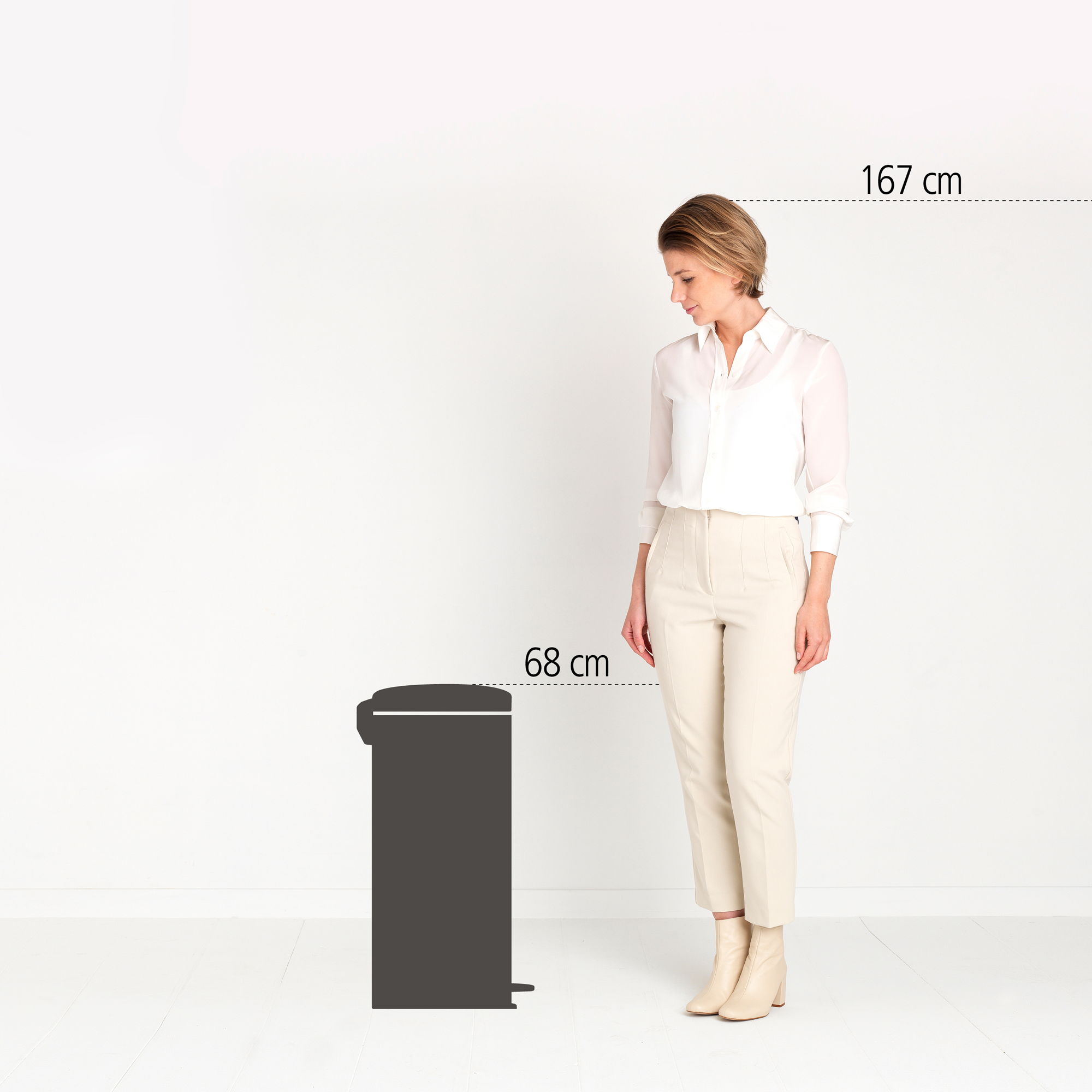 Een vrouw staat naast een donkere prullenbak van 68 cm. Haar lengte is 167 cm.