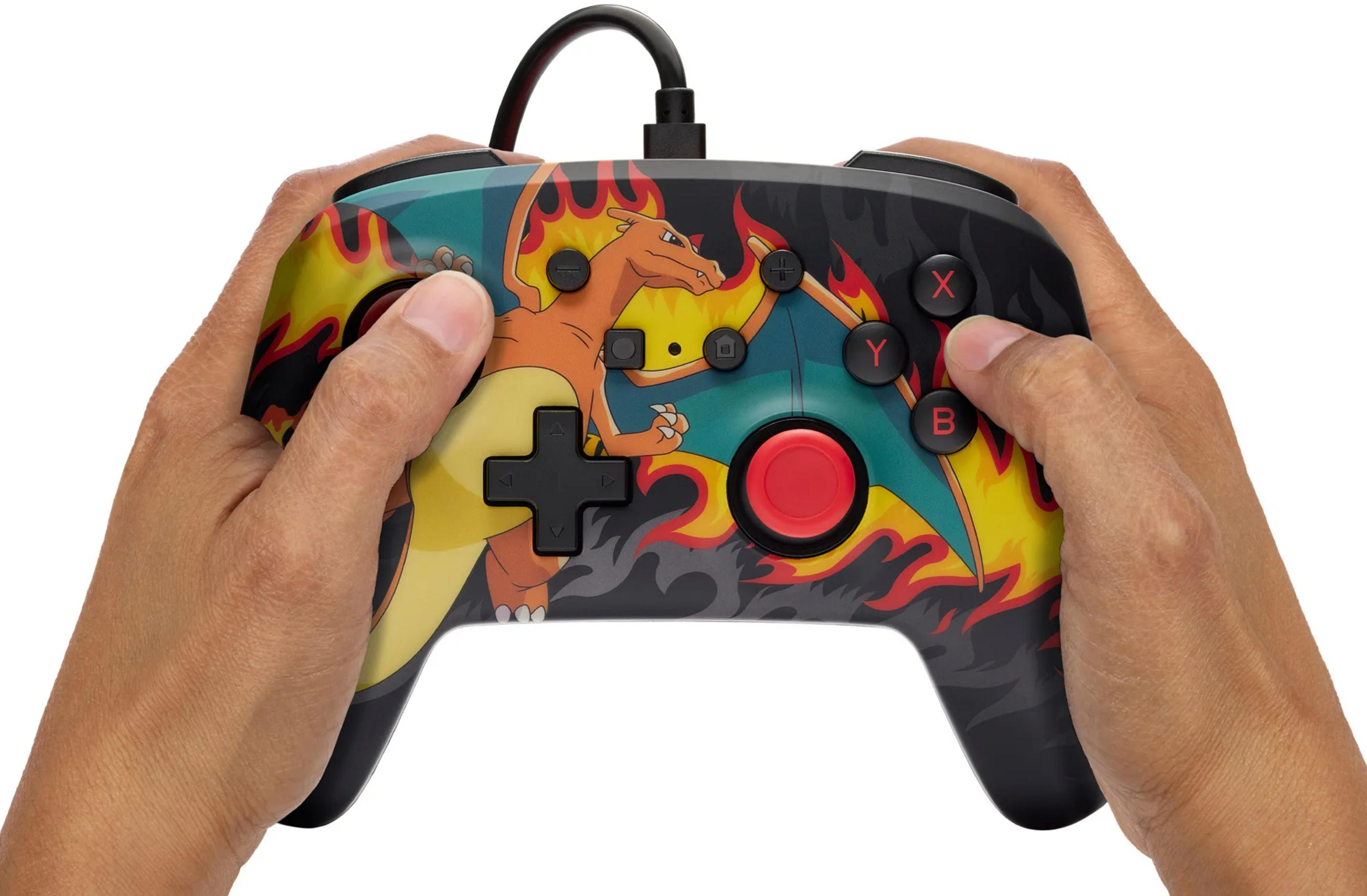 Mani che tengono un controller di gioco con Charizard e fiamme.