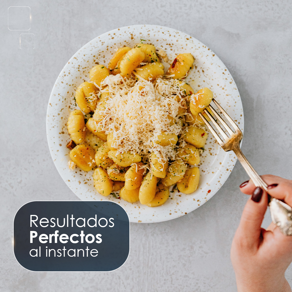 Gnocchi cubiertos con queso rallado en un plato, sostenido por una mano con un tenedor.
