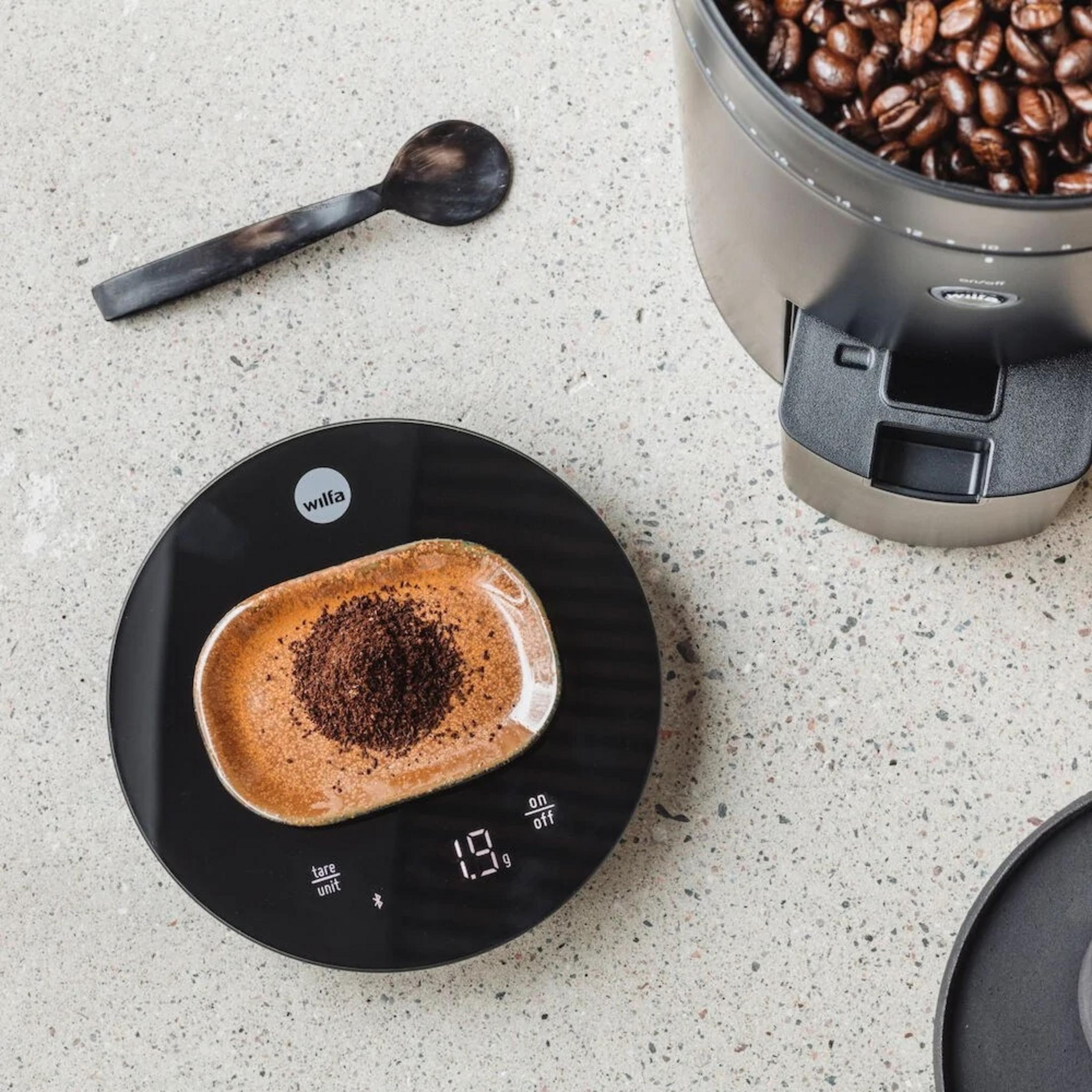 Kaffeebohnen und gemahlener Kaffee auf einer Waage mit Löffel.
