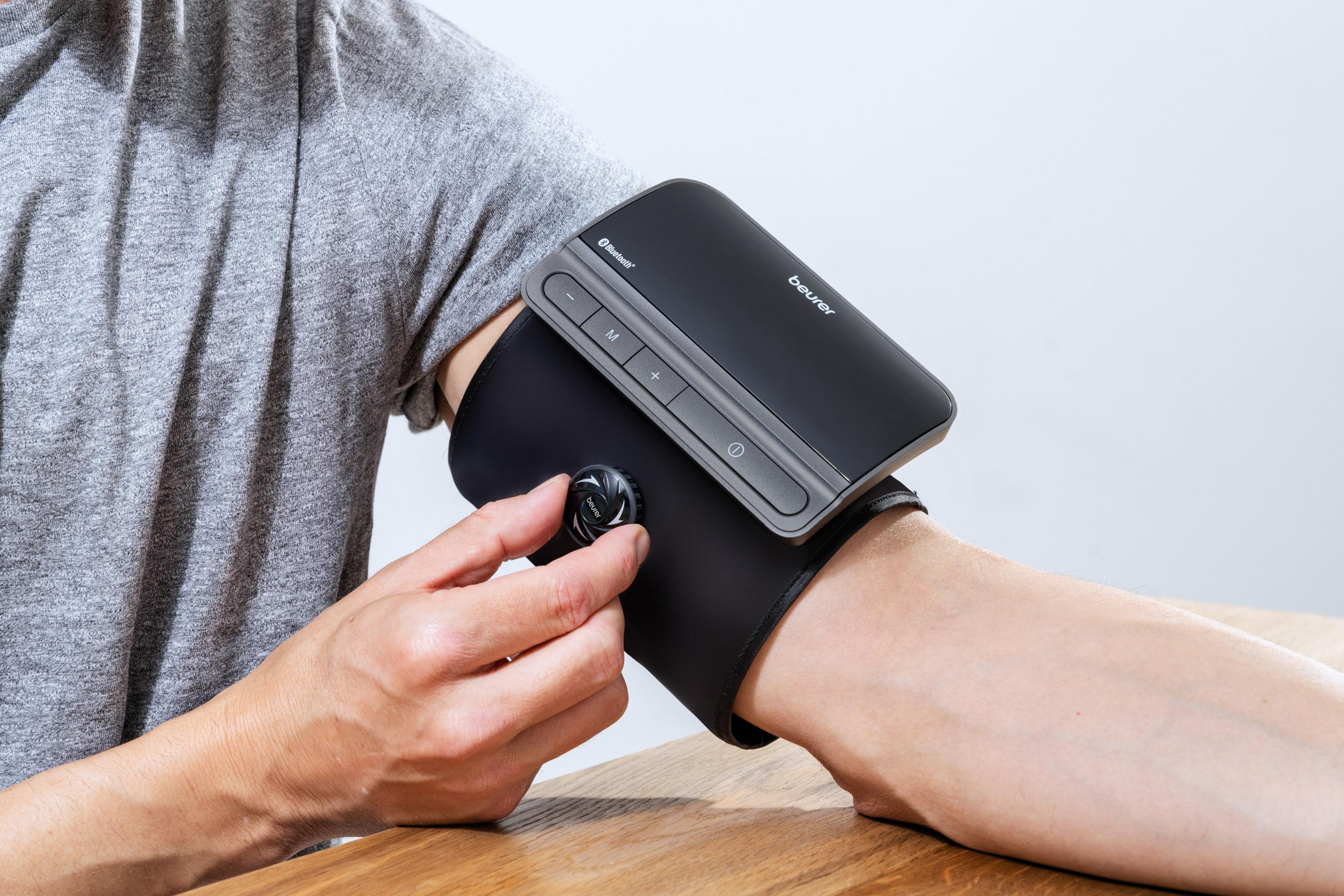 Person mit Blutdruckmessgerät am Arm