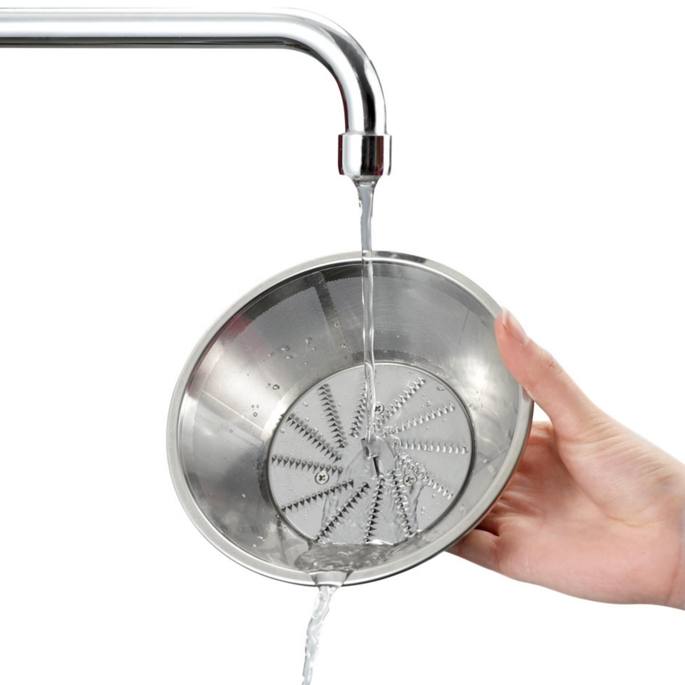 Wasser fließt aus einem Wasserhahn in einen Metallfilter mit scharfen Klingen.