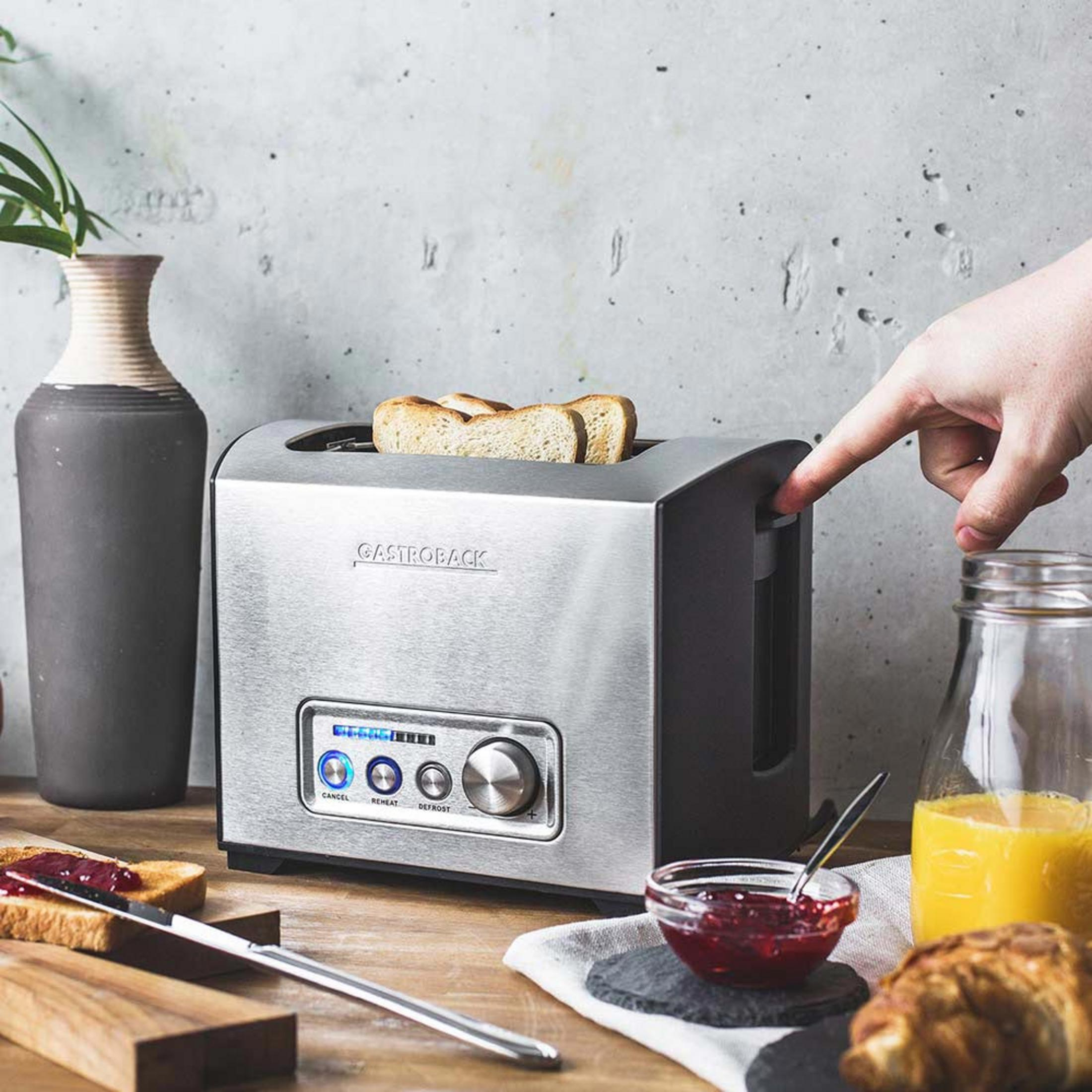 Ein silberner Toaster mit Toast, Marmelade, Orangensaft und einem Croissant.