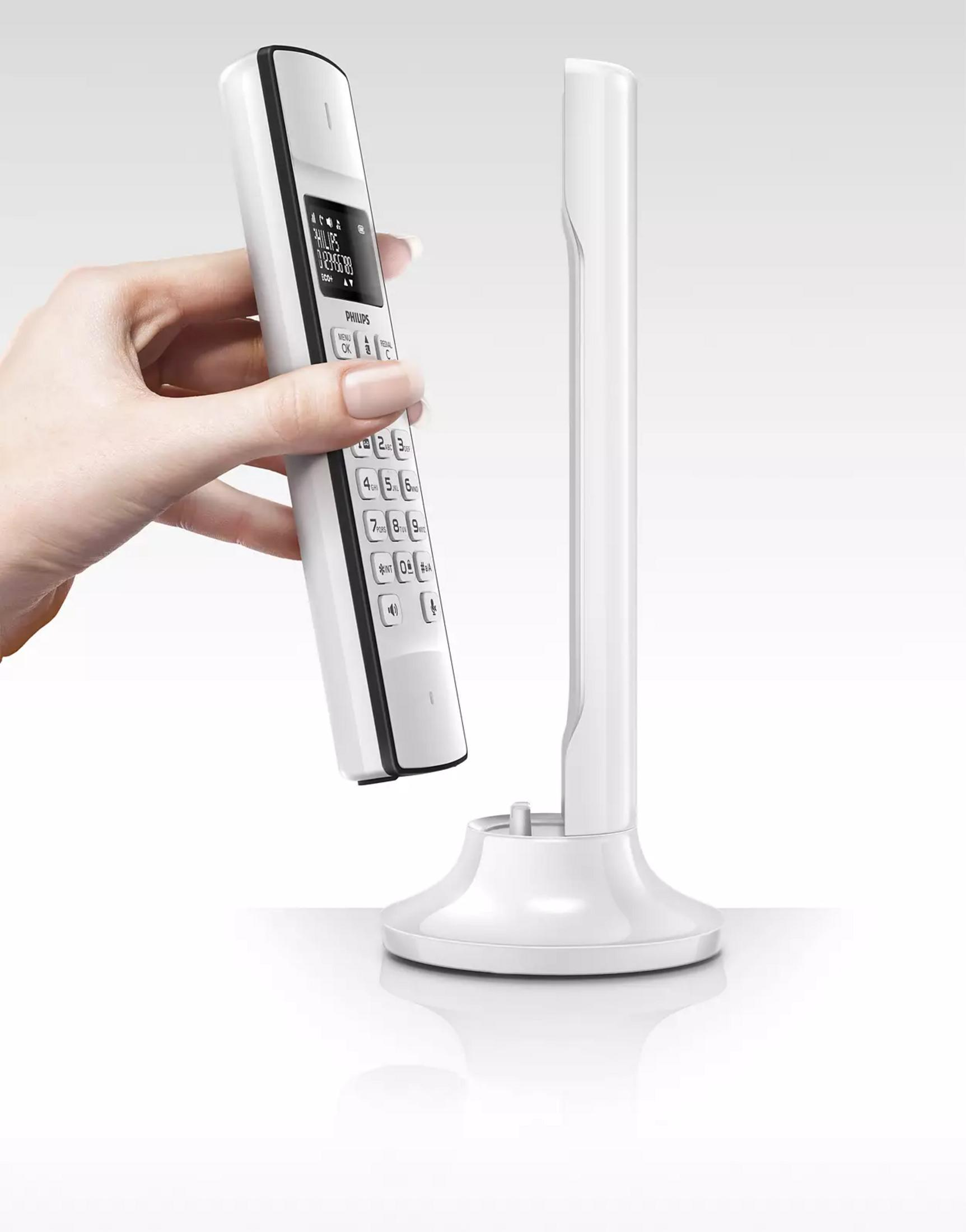 Une main tient un téléphone sans fil blanc au-dessus d'une station de charge.