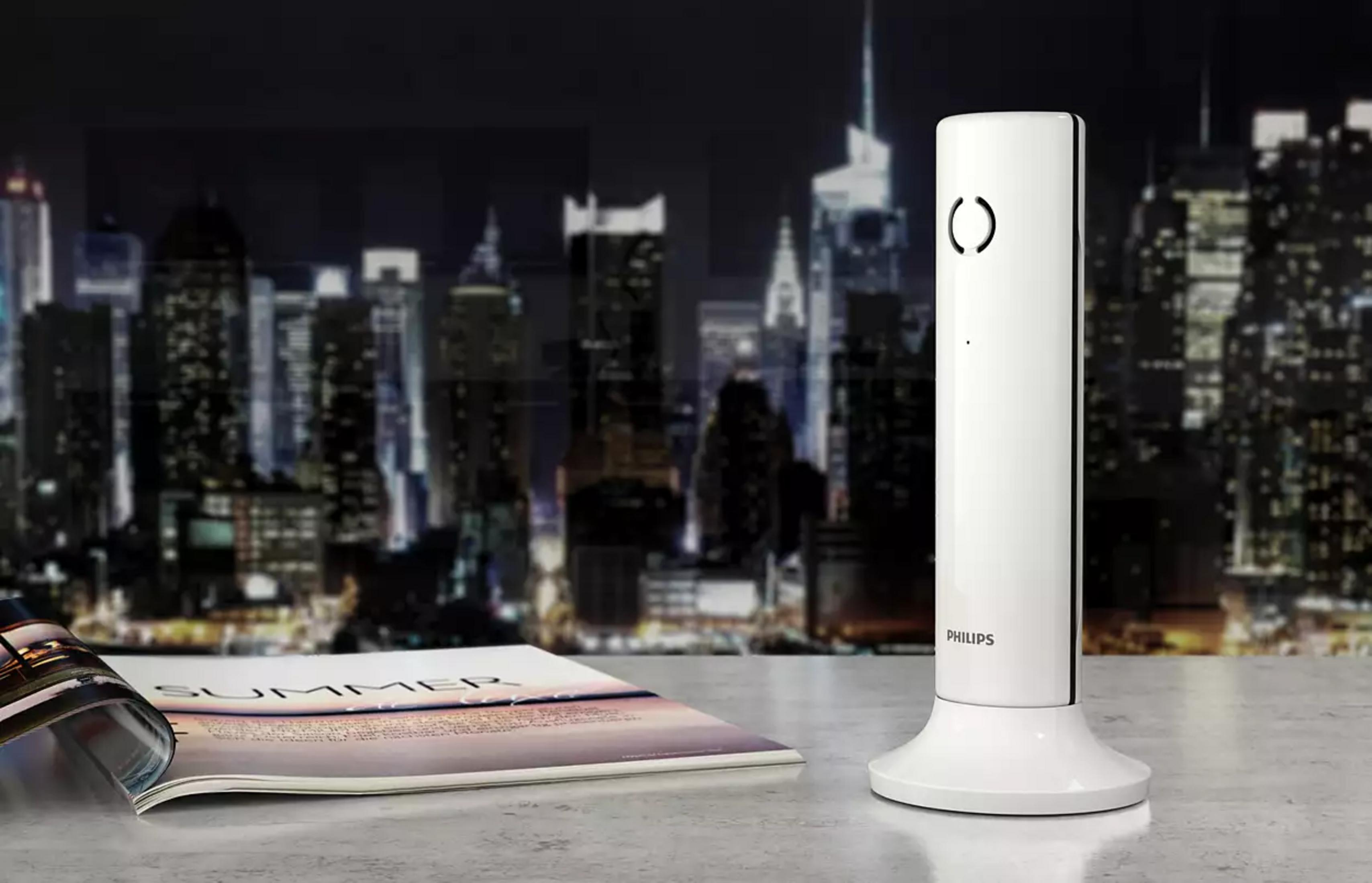 Un téléphone Philips blanc à côté d'un magazine intitulé SUMMER.