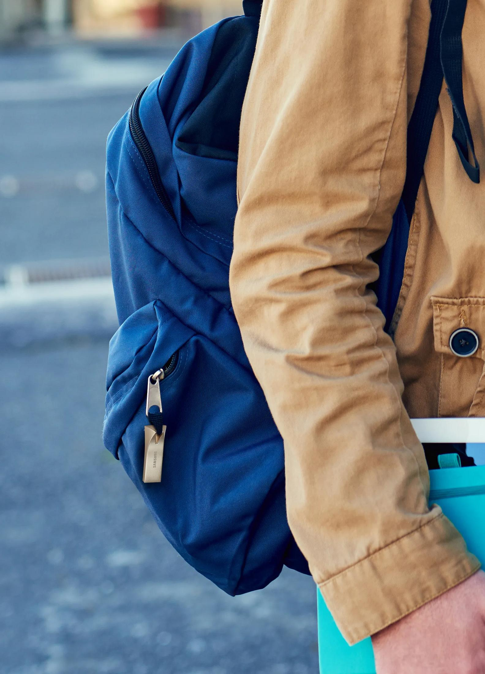 Una persona con mochila azul y chaqueta beige.