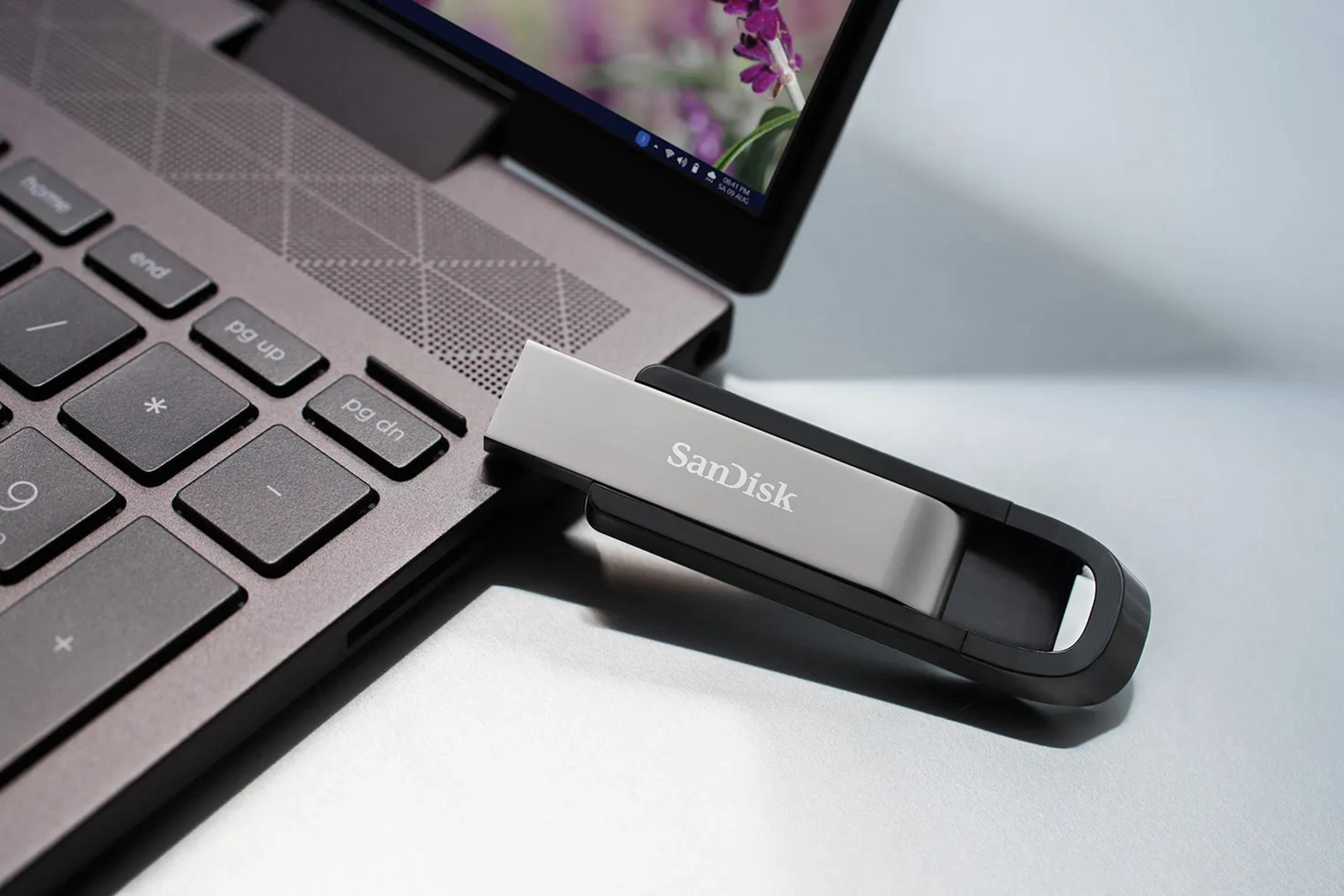 Pendrive SanDisk jest podłączony do laptopa obok klawiatury.