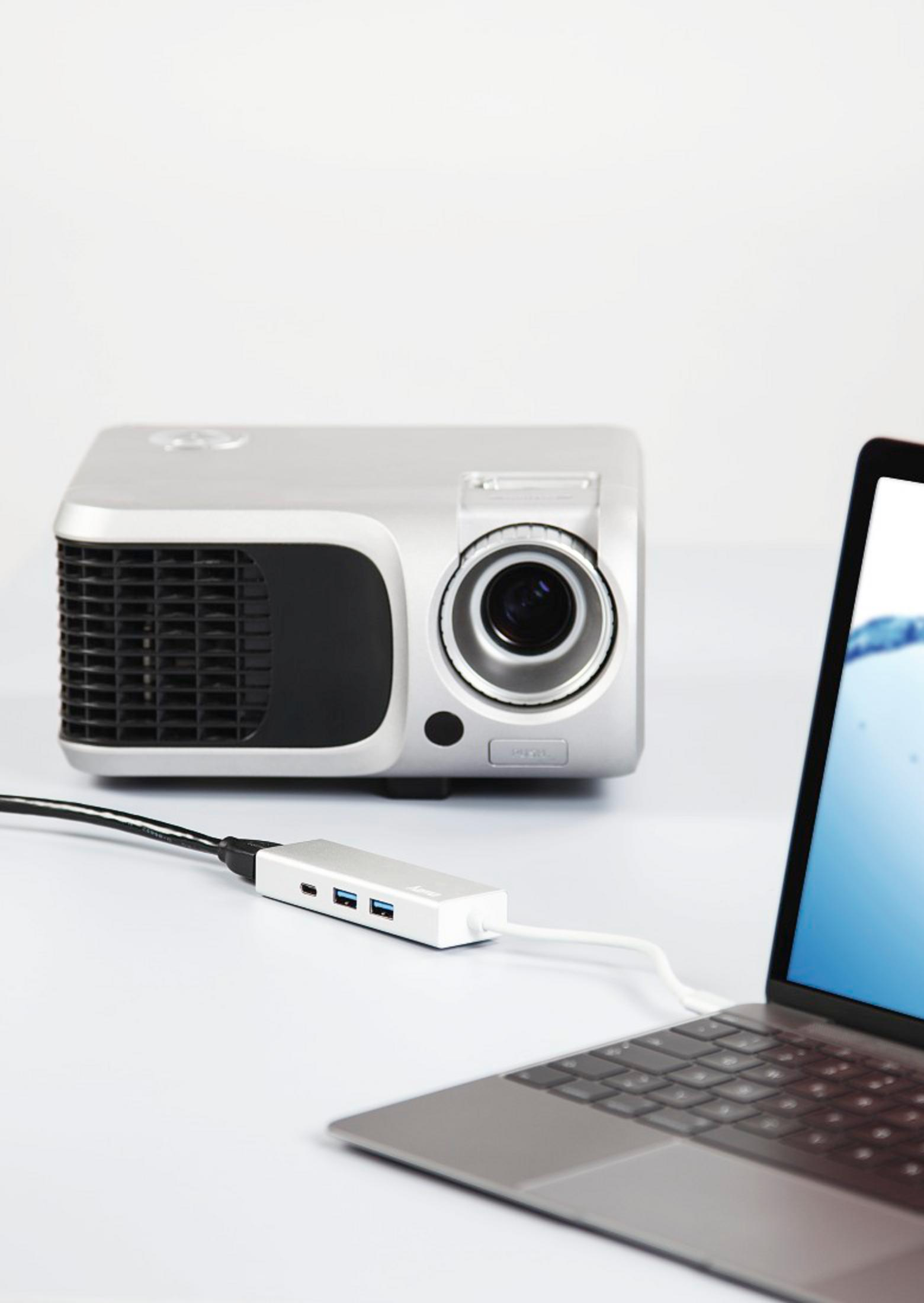 Ein silberner Projektor und ein Laptop sind über einen weißen Hub verbunden.