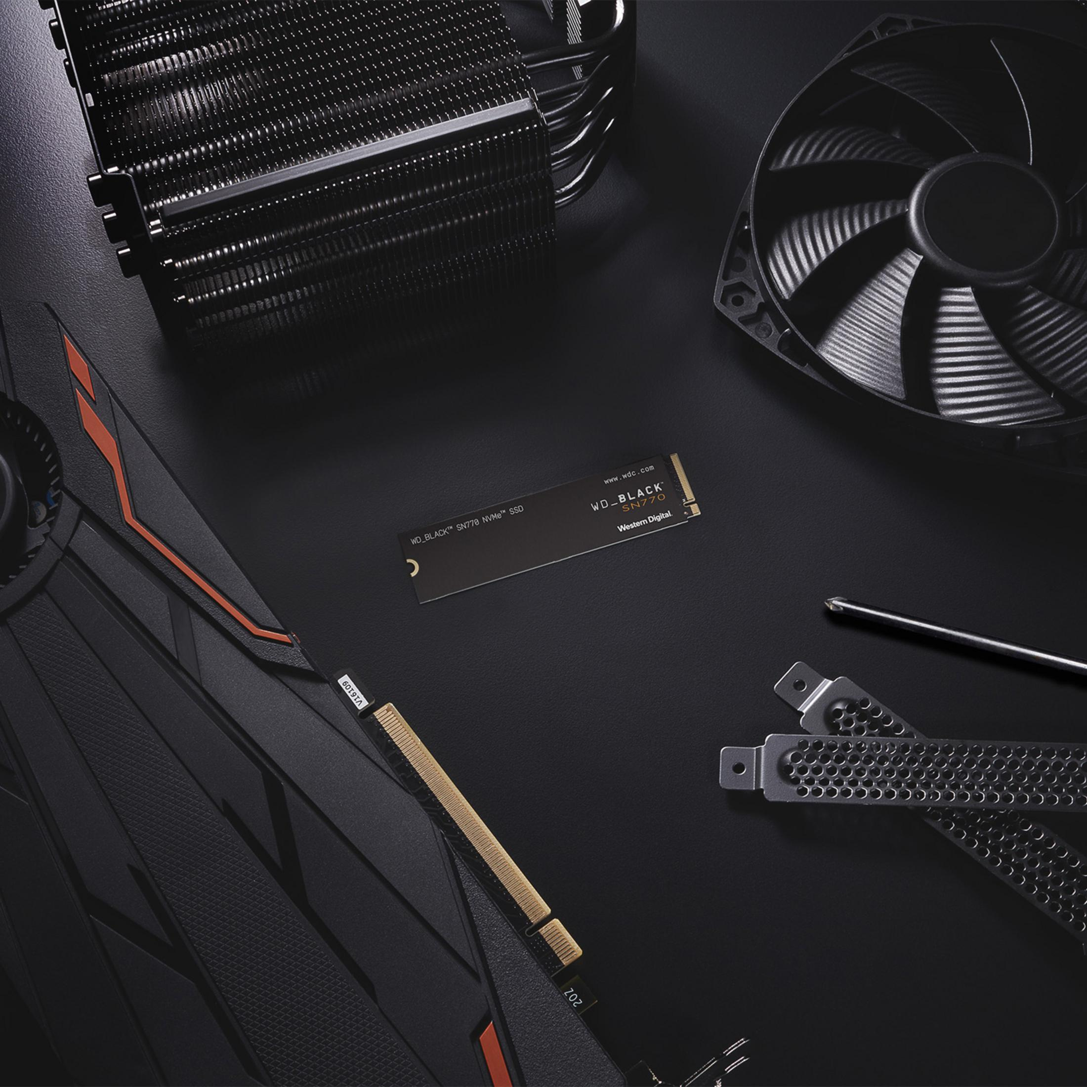 Ventilador de PC negro, disipador de CPU, SSD y tarjeta gráfica sobre fondo negro.