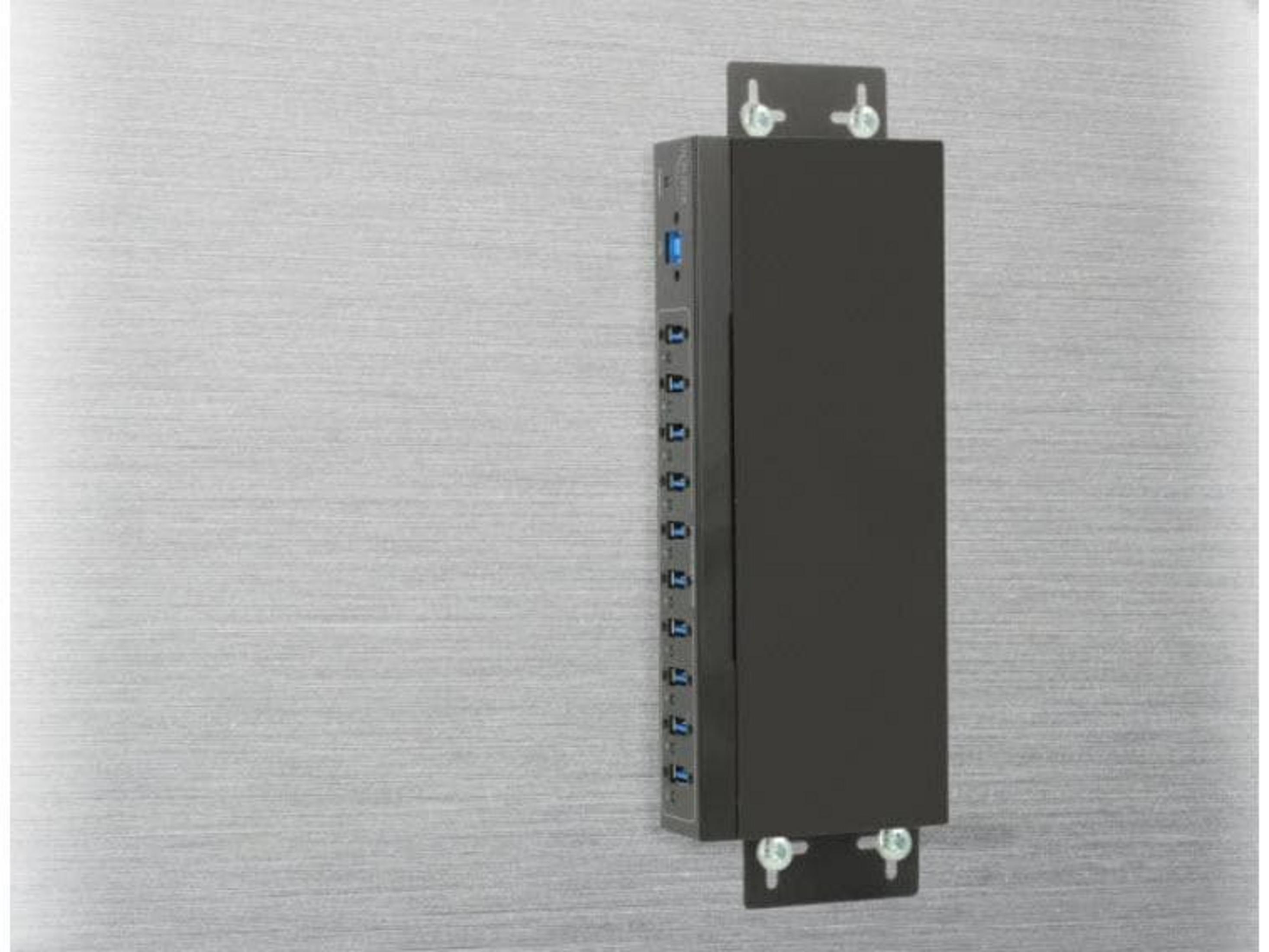 Ein schwarzes USB-Hub mit mehreren Anschlüssen, an einer metallischen Oberfläche montiert.