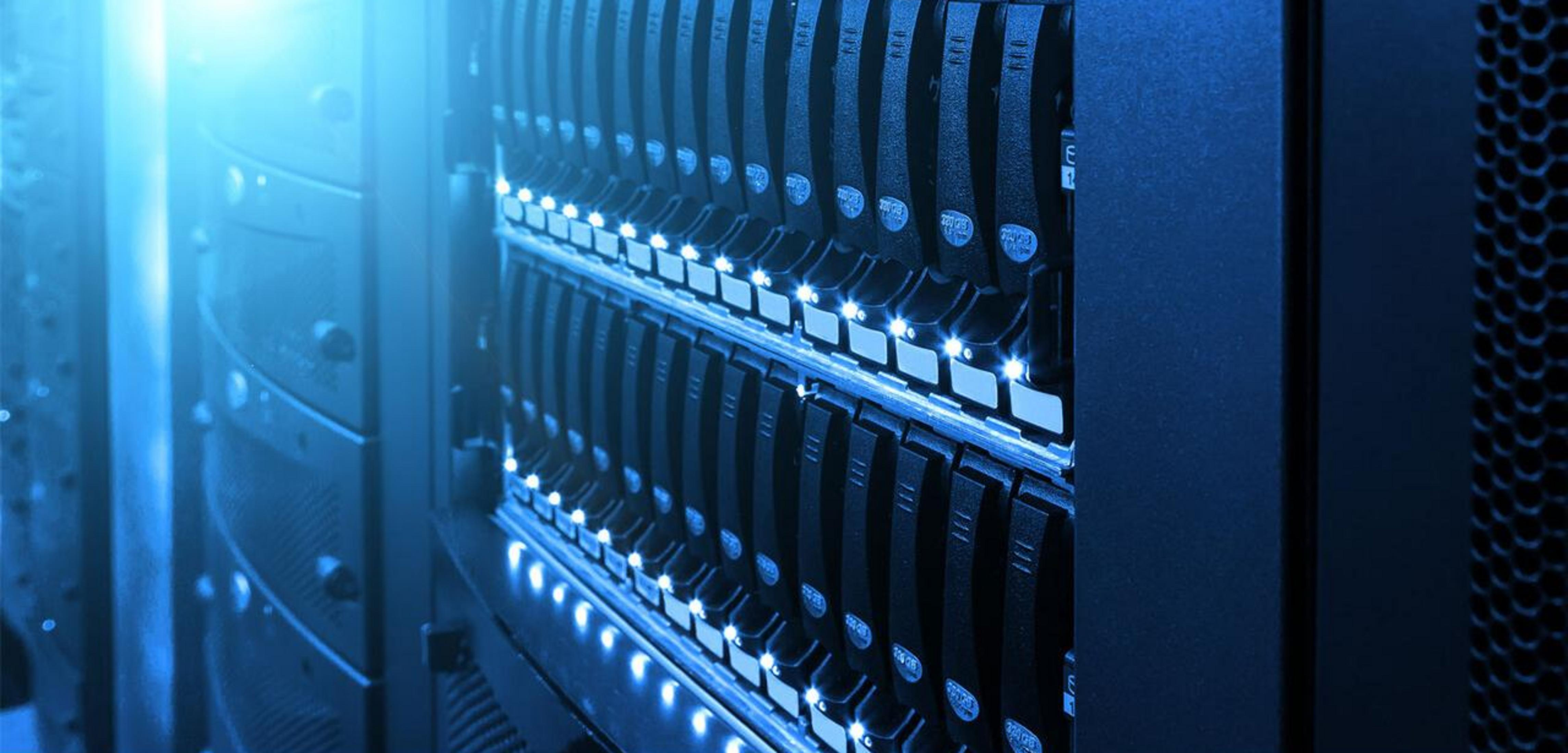 Rzędy dysków twardych serwera z niebieskimi światłami w ciemnym centrum danych.