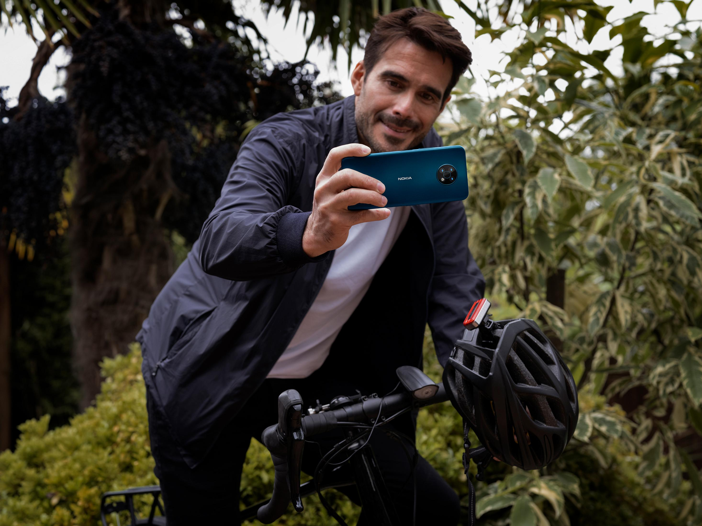 Mann mit Handy und Fahrradhelm draußen.