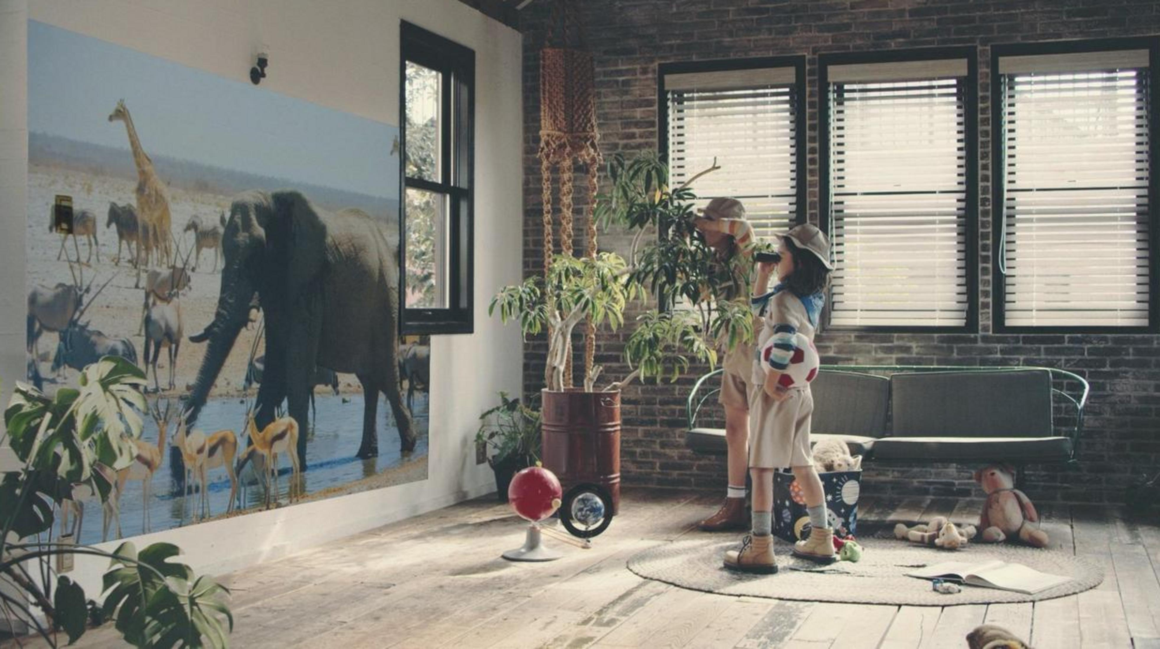 Due bambini guardano nel binocolo in una stanza con un murale di animali.