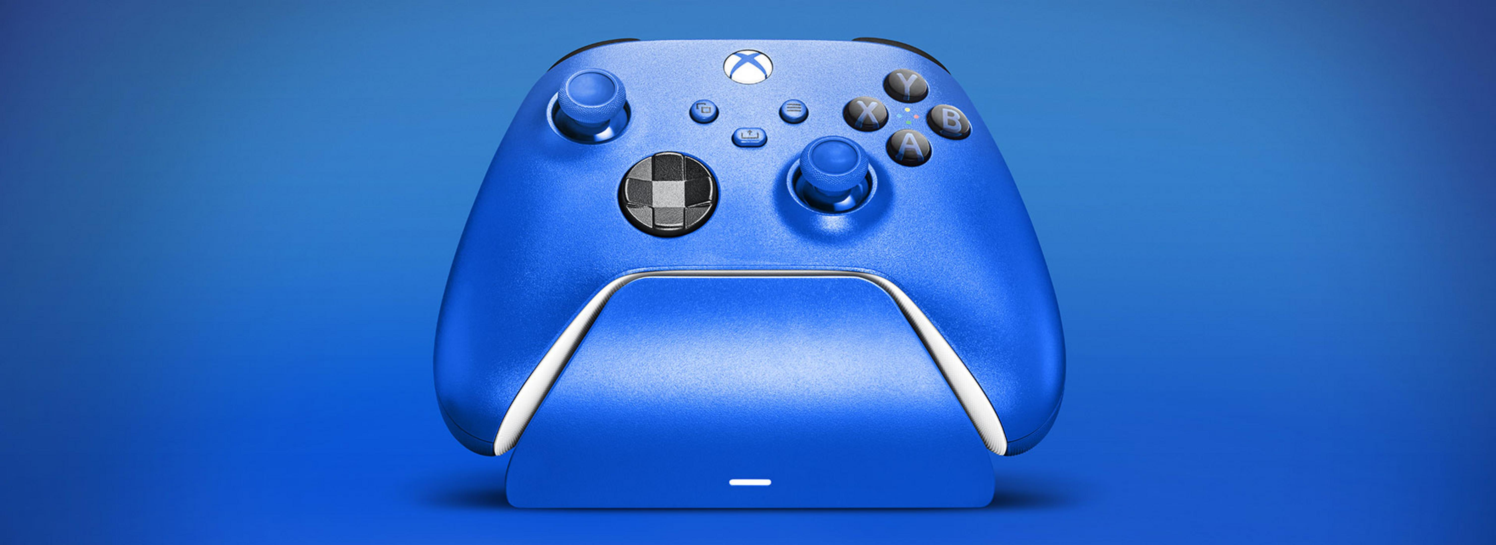 Un controller Xbox blu poggia su una base di ricarica blu su sfondo blu.