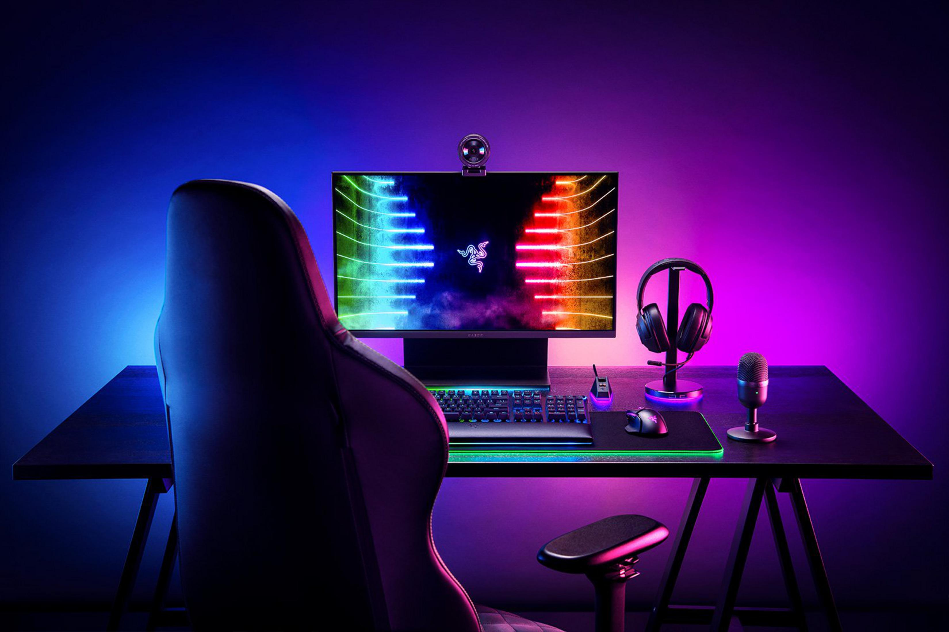 Ein Gaming-Setup mit Stuhl, Schreibtisch, Monitor, Tastatur, Maus, Kopfhörern und Mikrofon.