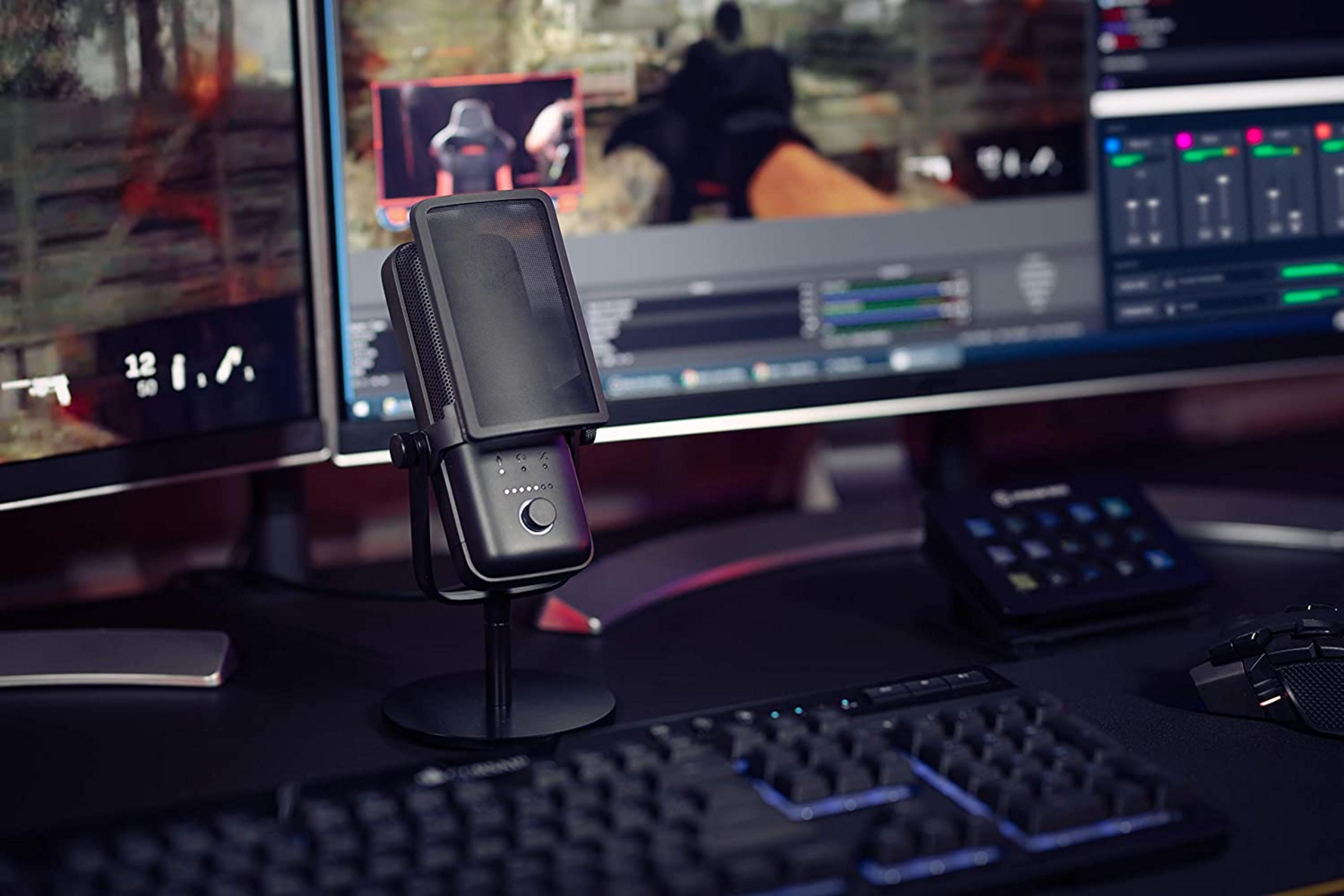 Un microfono nero davanti a due monitor che mostrano giochi e software di streaming.