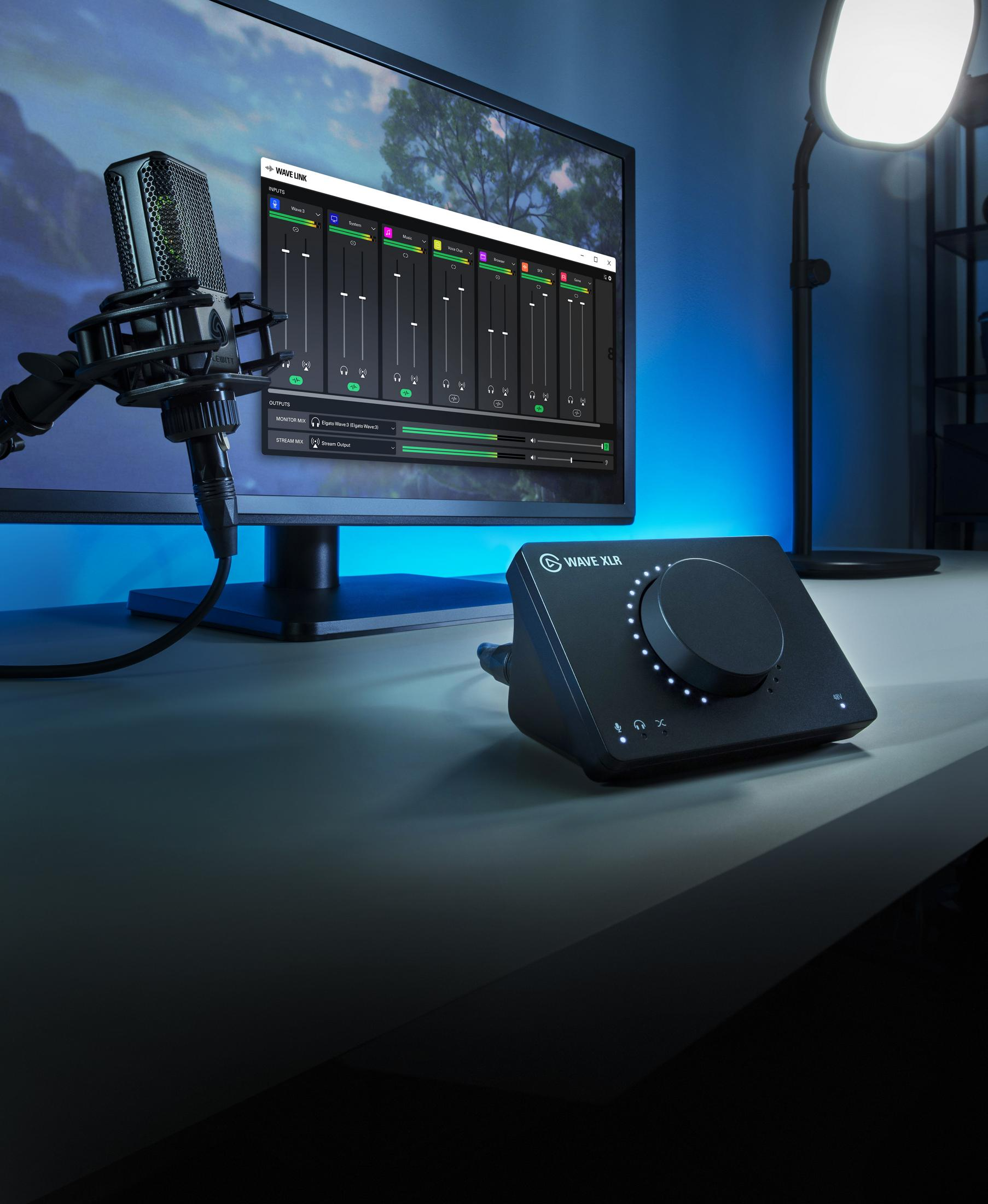Microfono, mixer e monitor su una scrivania con illuminazione blu.