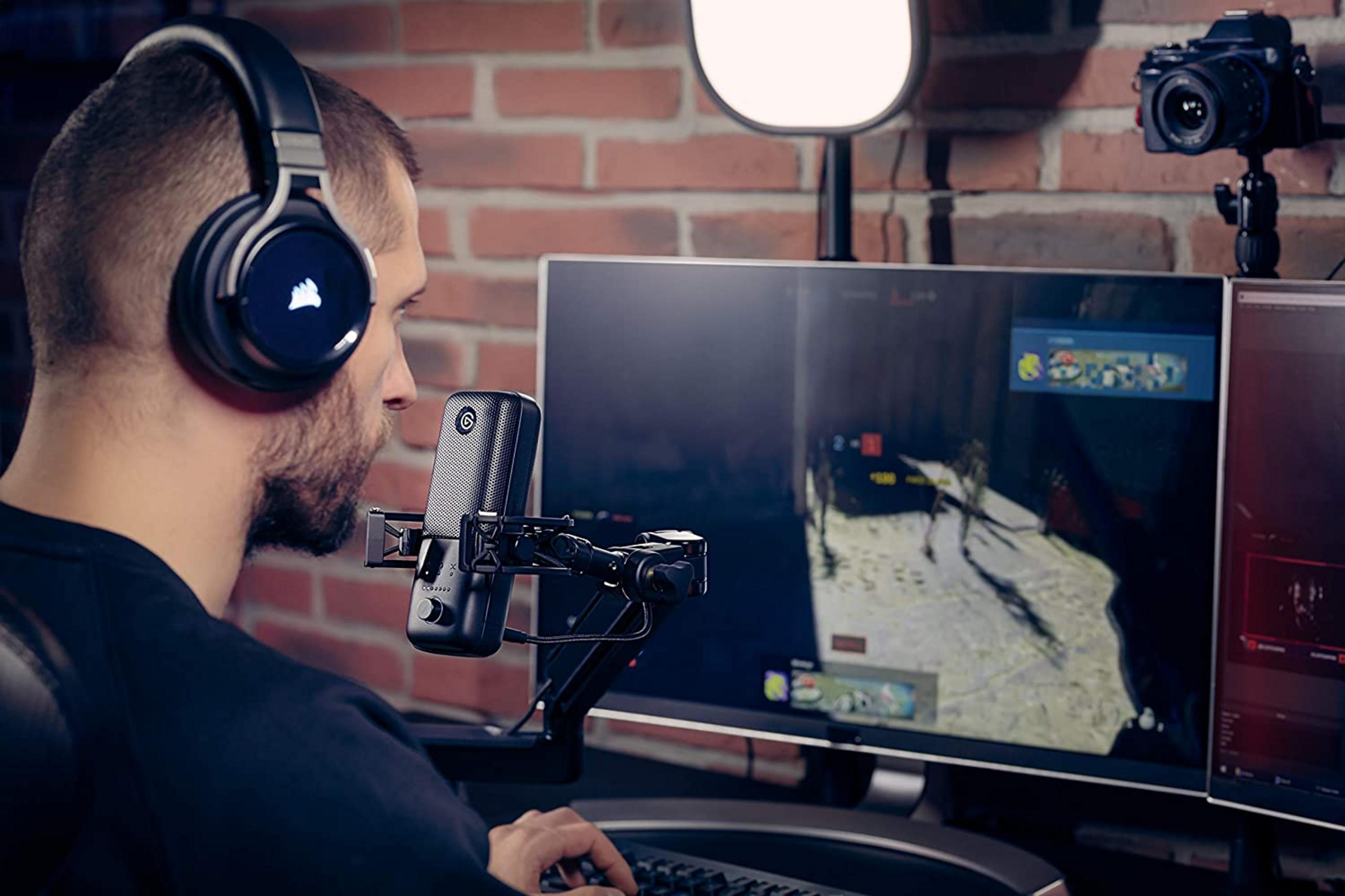 Mann mit Kopfhörern spielt Videospiel, Mikrofon vor PC-Monitor mit Kamera.