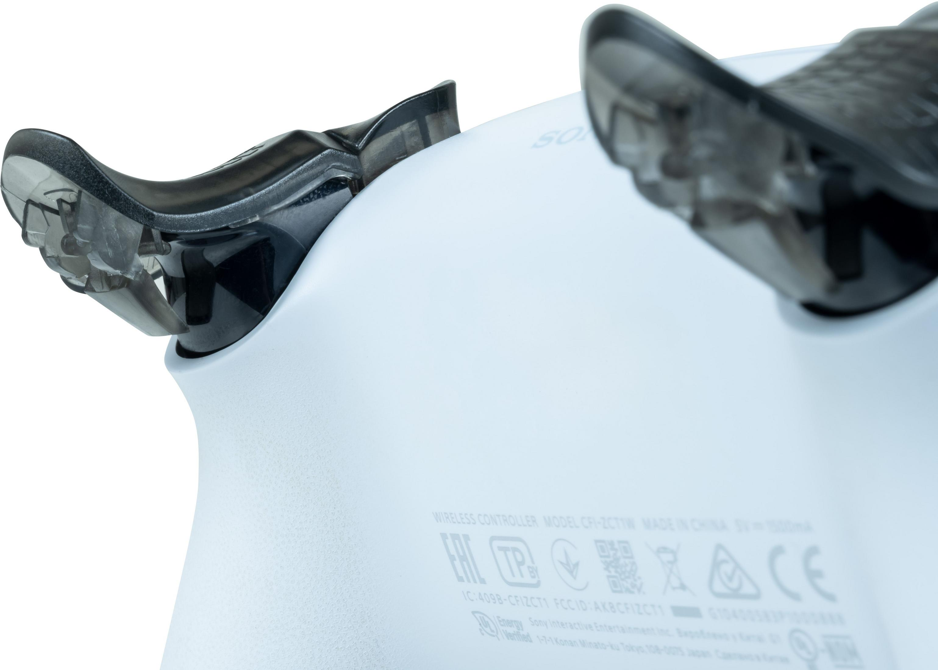 Zbliżenie białego kontrolera z czarnymi uchwytami i oznaczeniami.