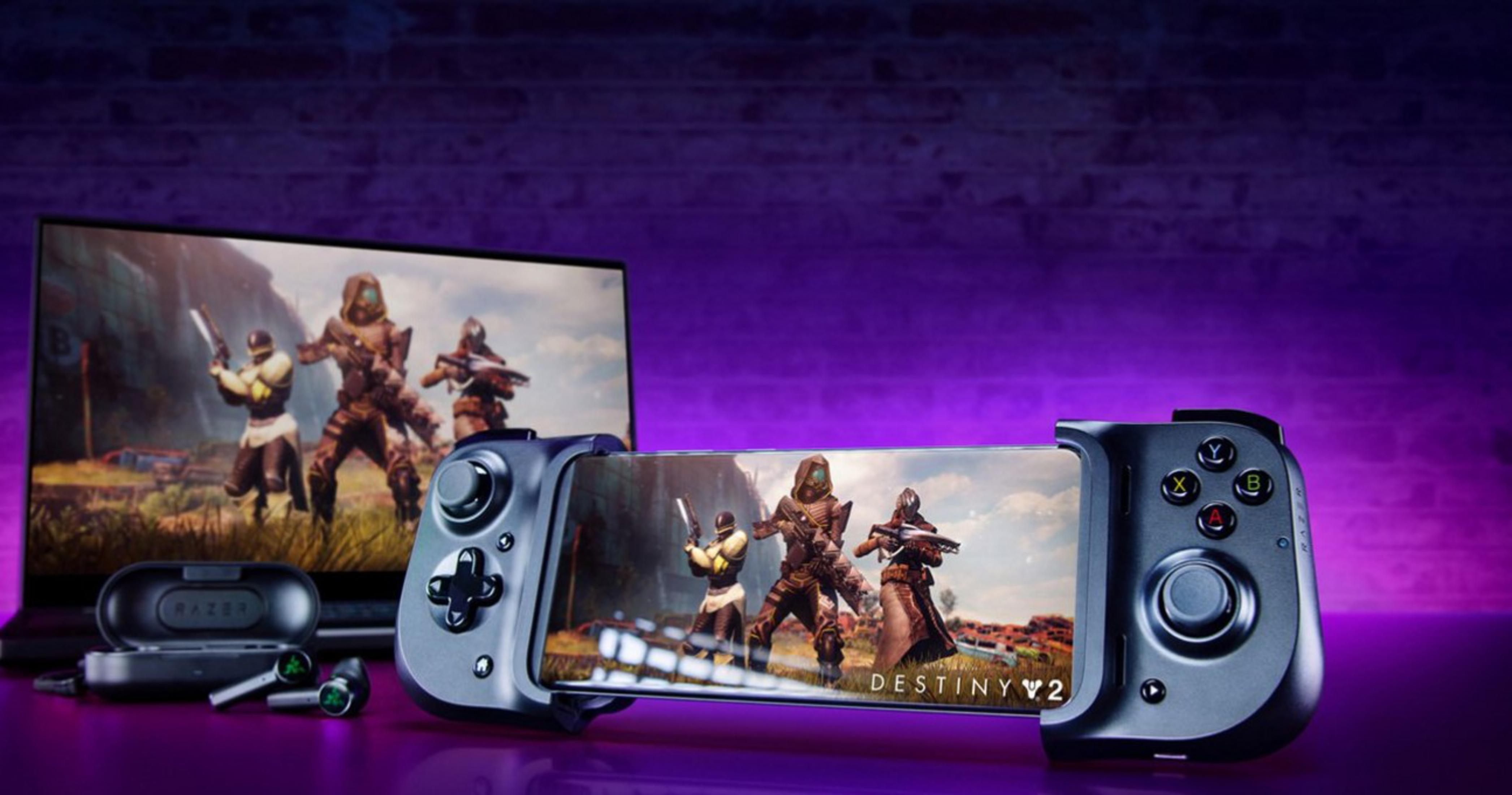 Un smartphone con mando de juegos y auriculares frente a un portátil mostrando un juego.