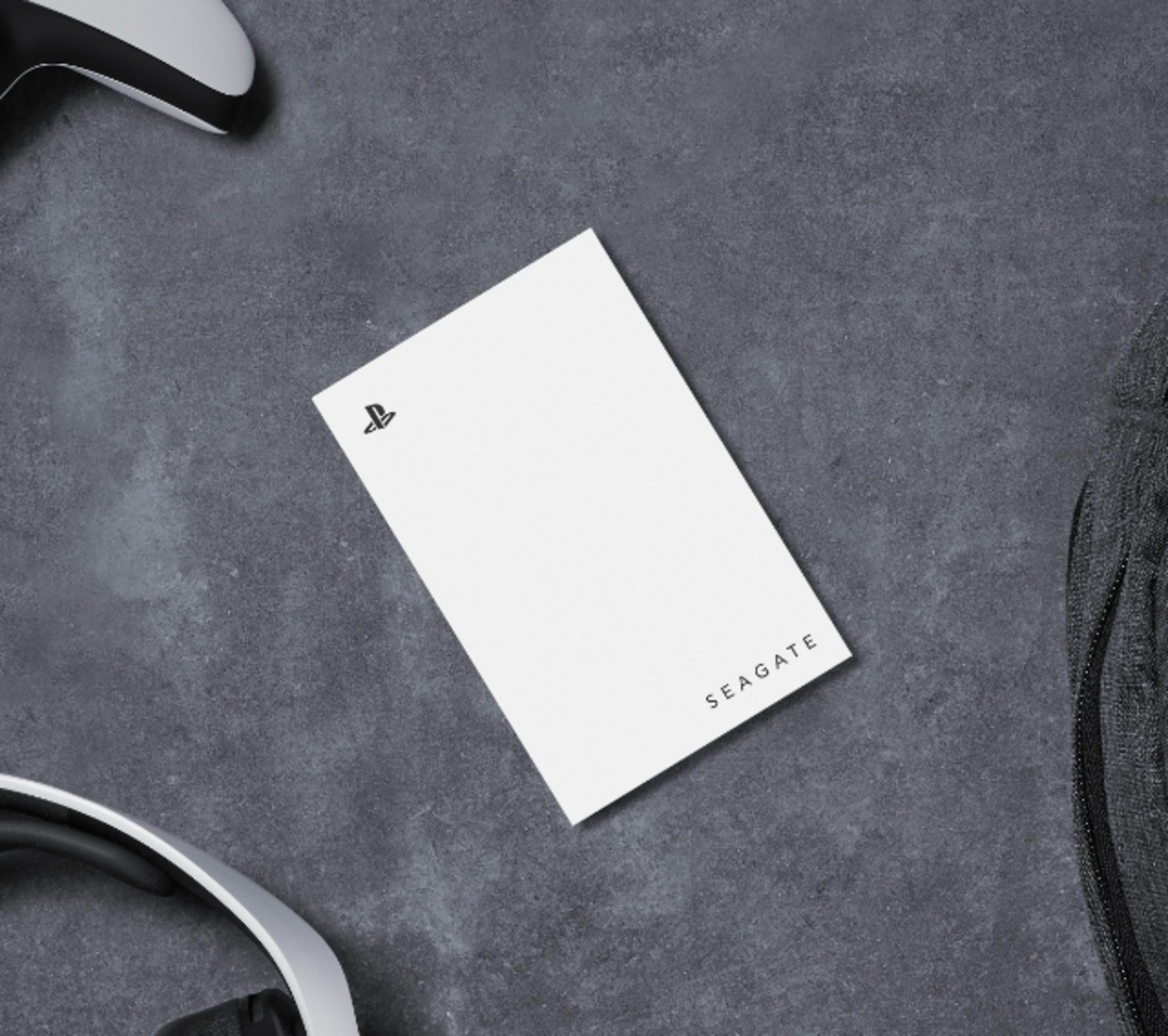 Biały dysk Seagate z logo PlayStation obok kontrolera i słuchawek.