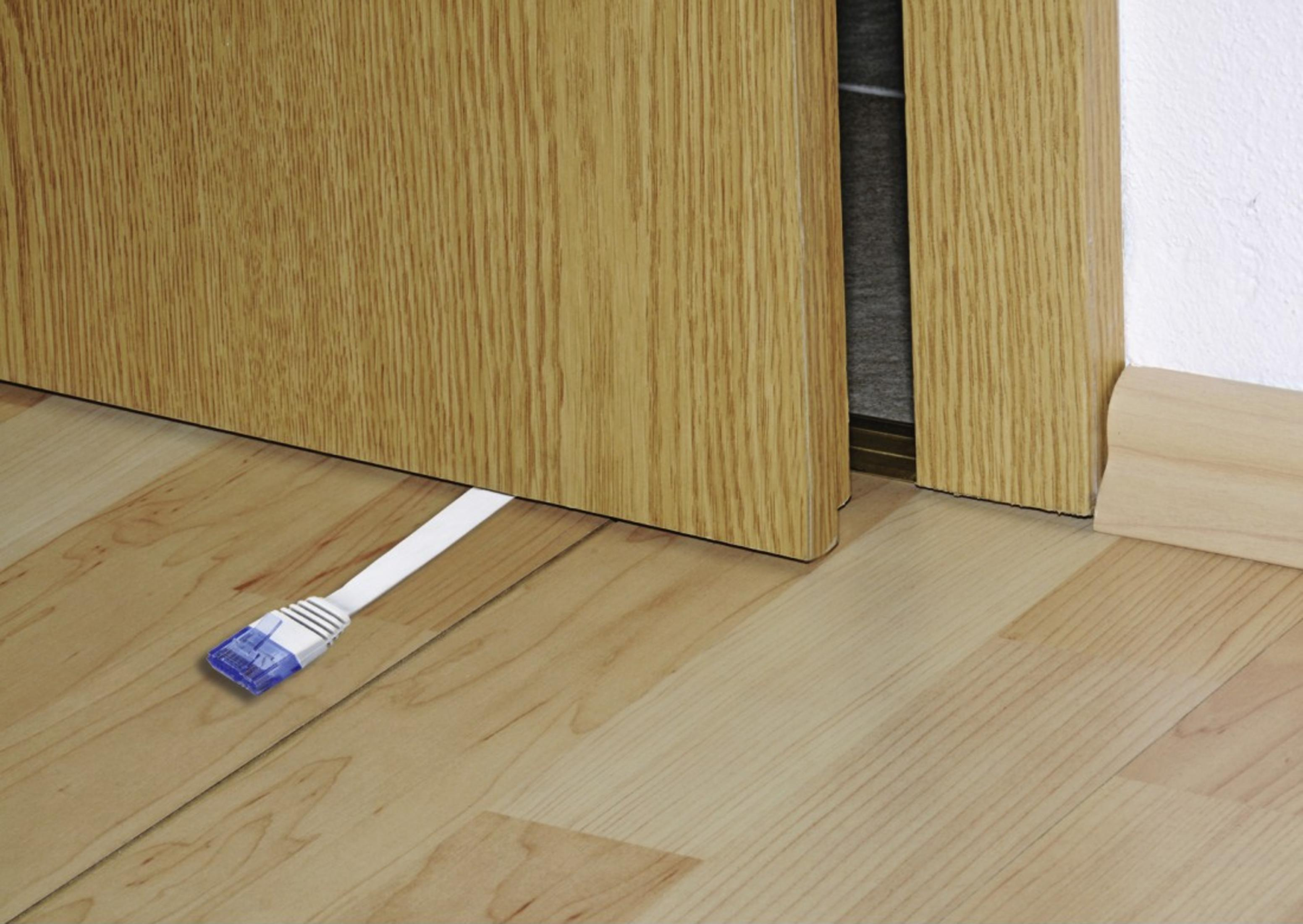 Un cavo di rete bianco con connettore blu su pavimento in legno.