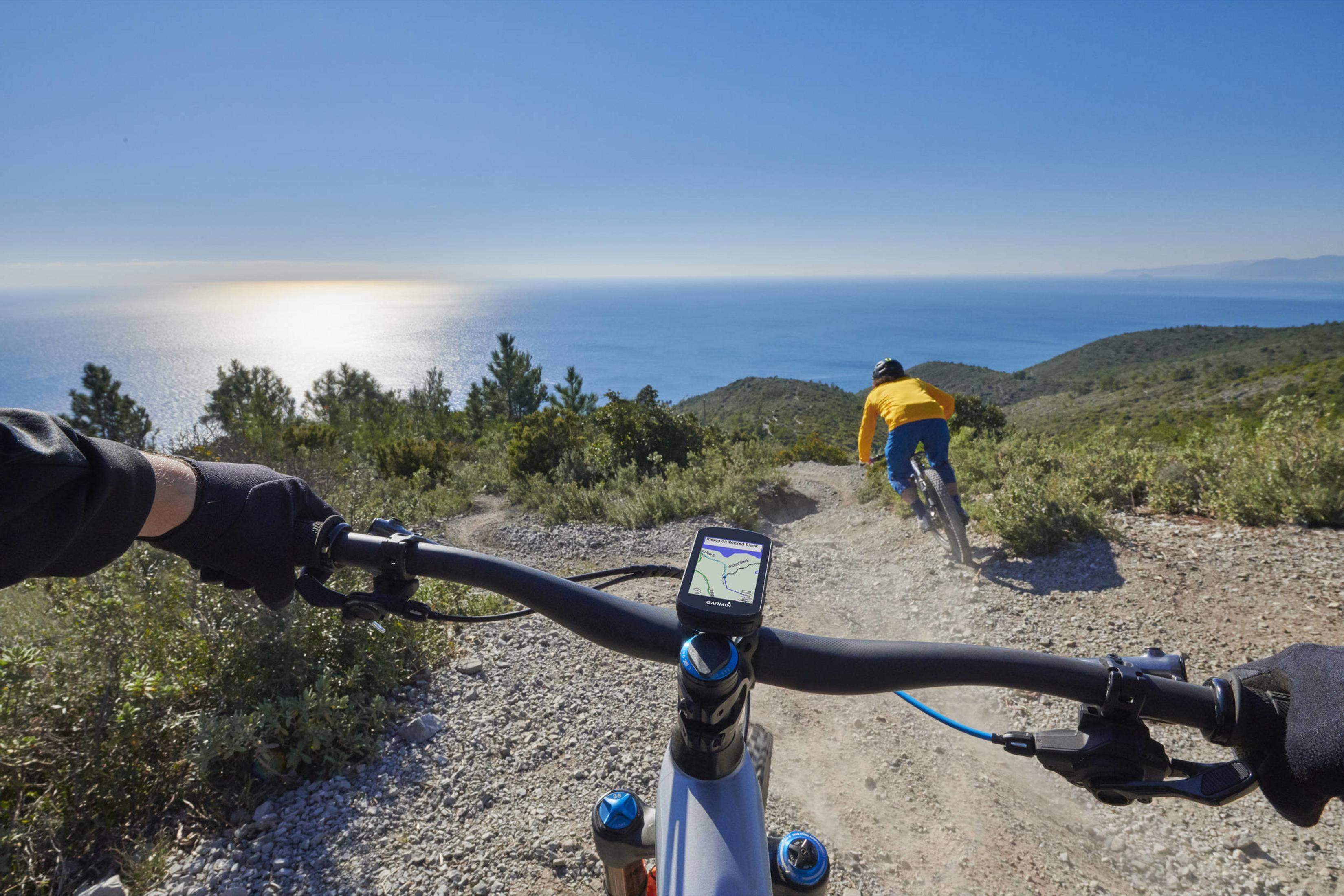 Ciclista de montaña descendiendo con vista al mar.