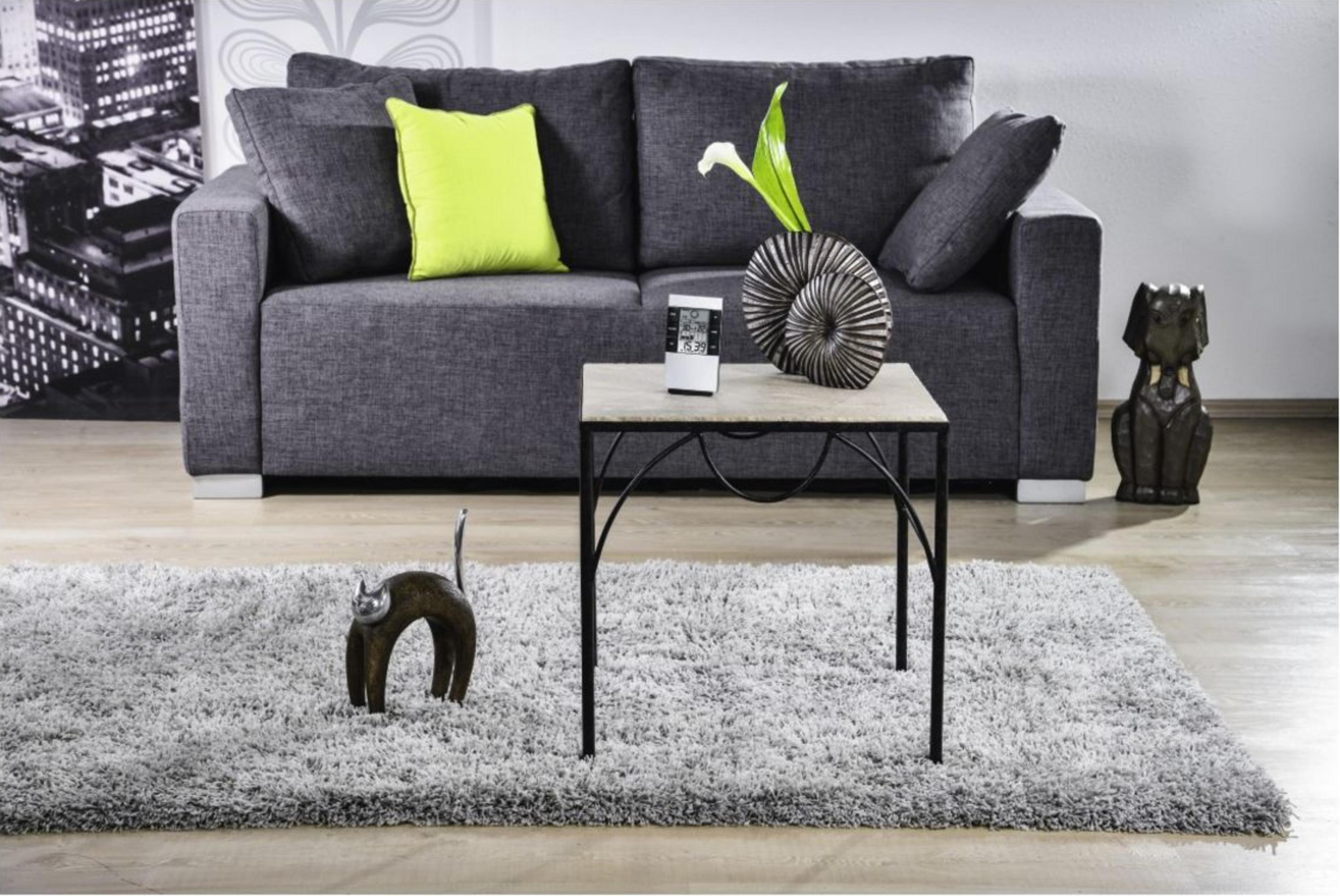Szara sofa, stolik kawowy z dekoracjami, dywan i figurka kota/psa.