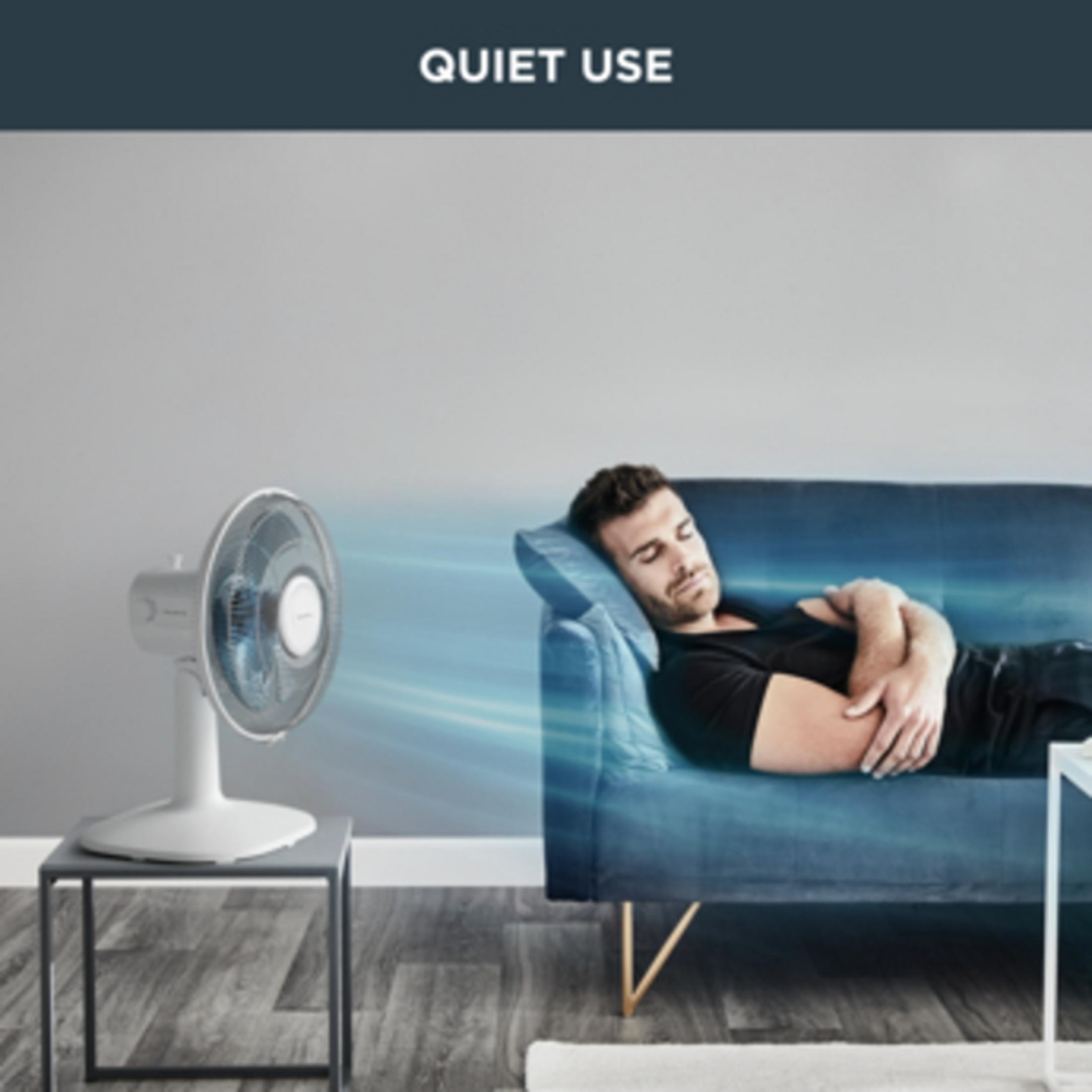 Mężczyzna śpi na kanapie, gdy wentylator cicho wieje.