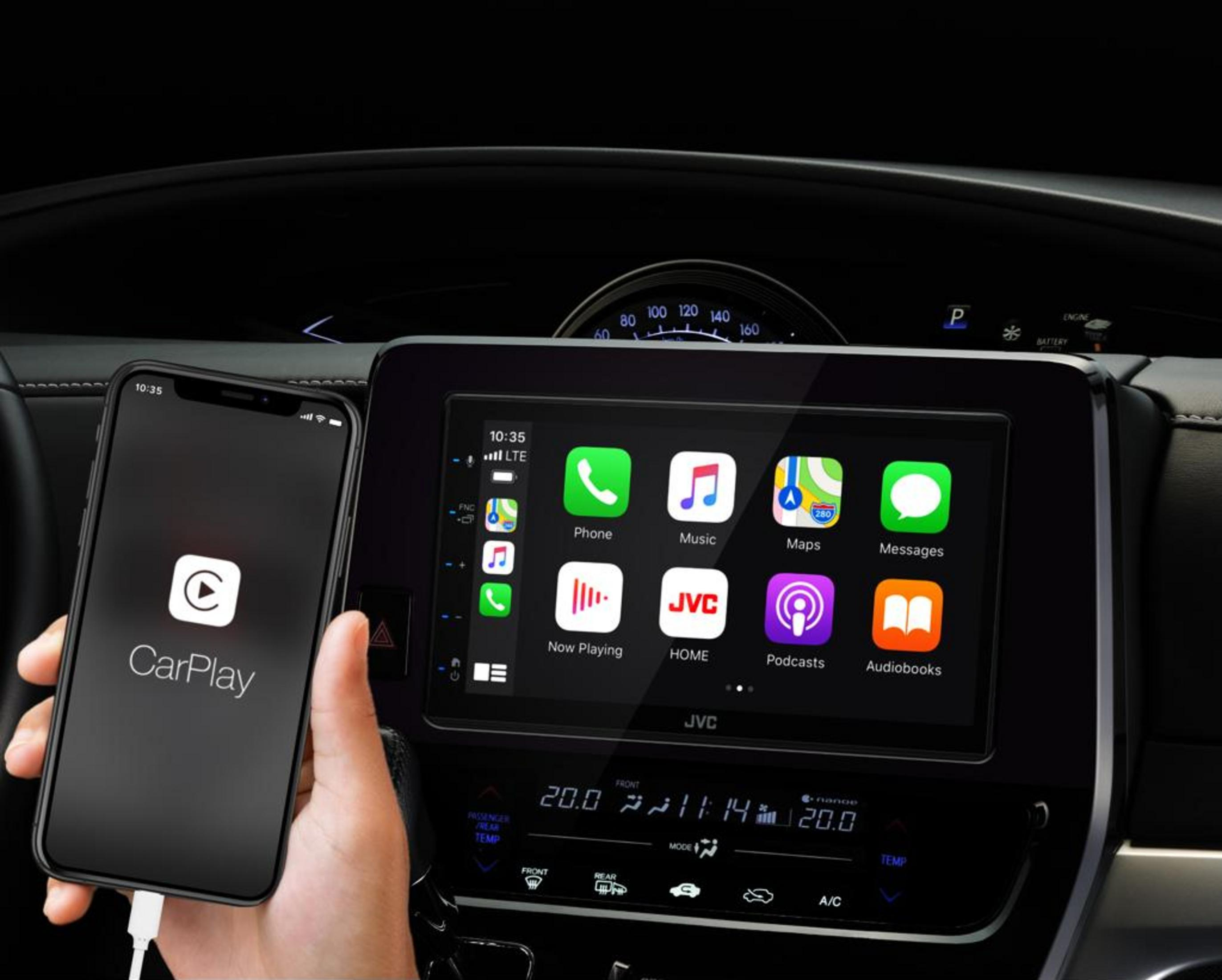 Ein iPhone mit CarPlay wird neben einem JVC-Infotainment-Bildschirm in einem Auto angezeigt.