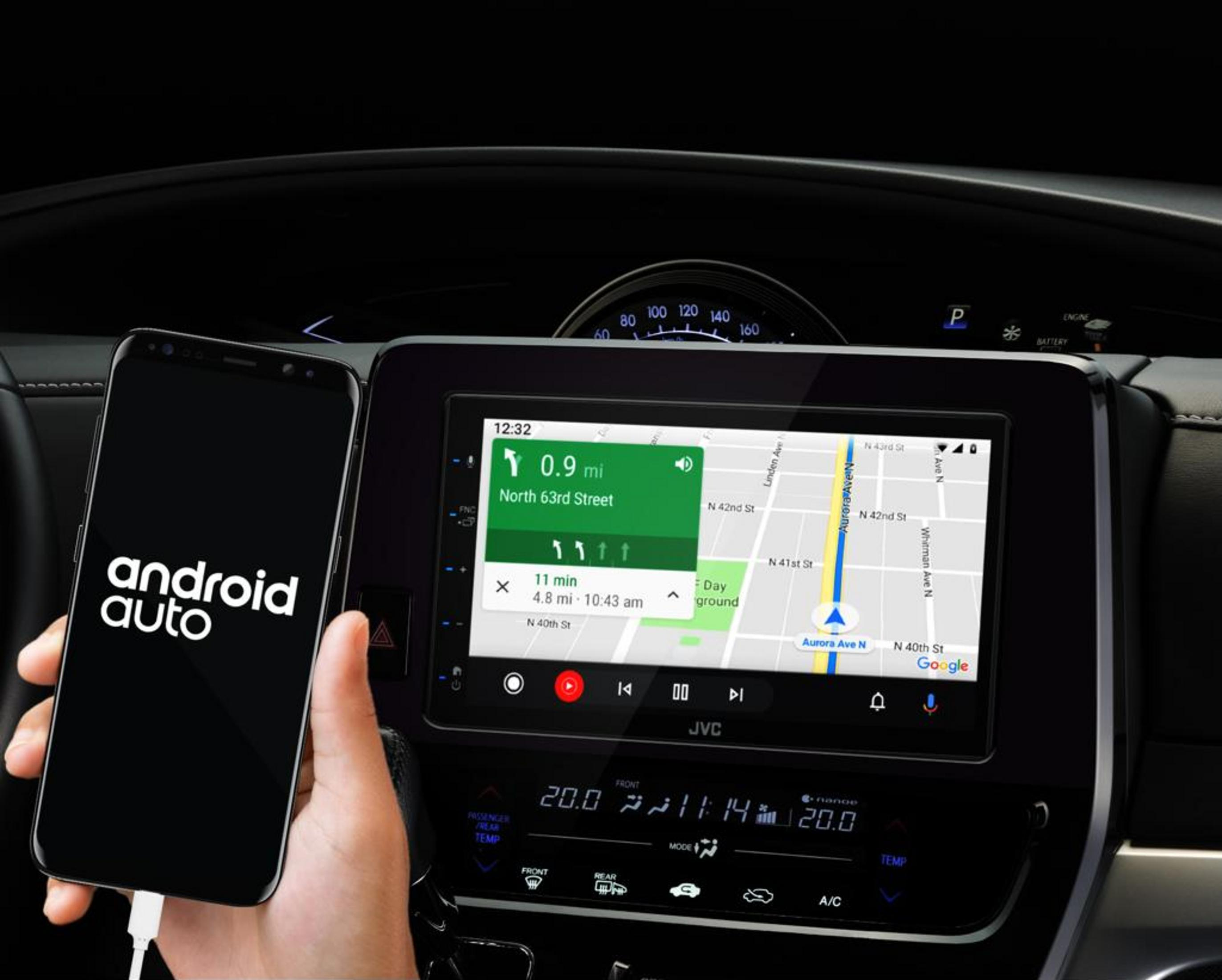 Hand hält Smartphone mit Android Auto vor Autodisplay mit Navigation.