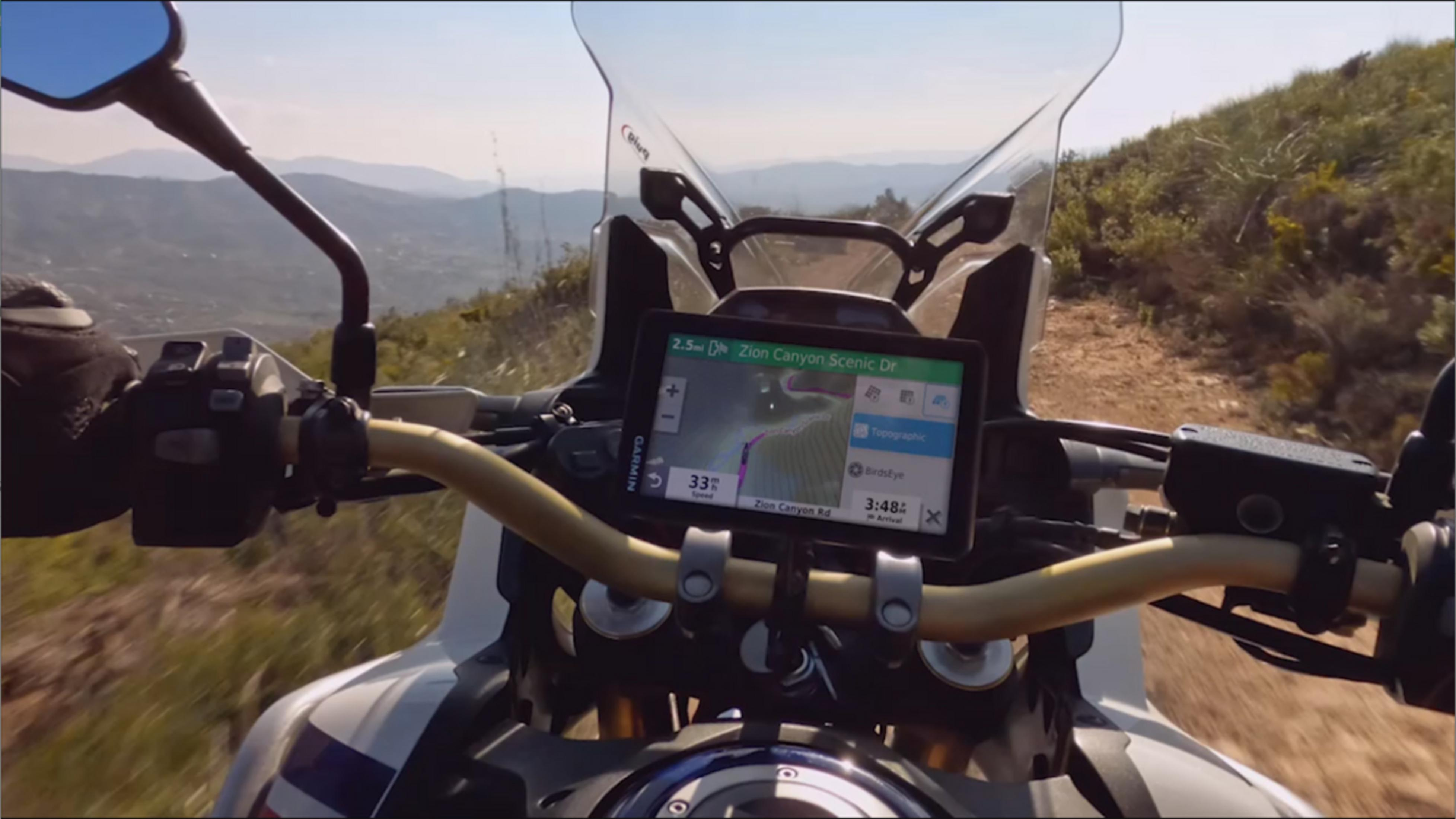 GPS moto mostra percorso su strada di montagna, con paesaggio.