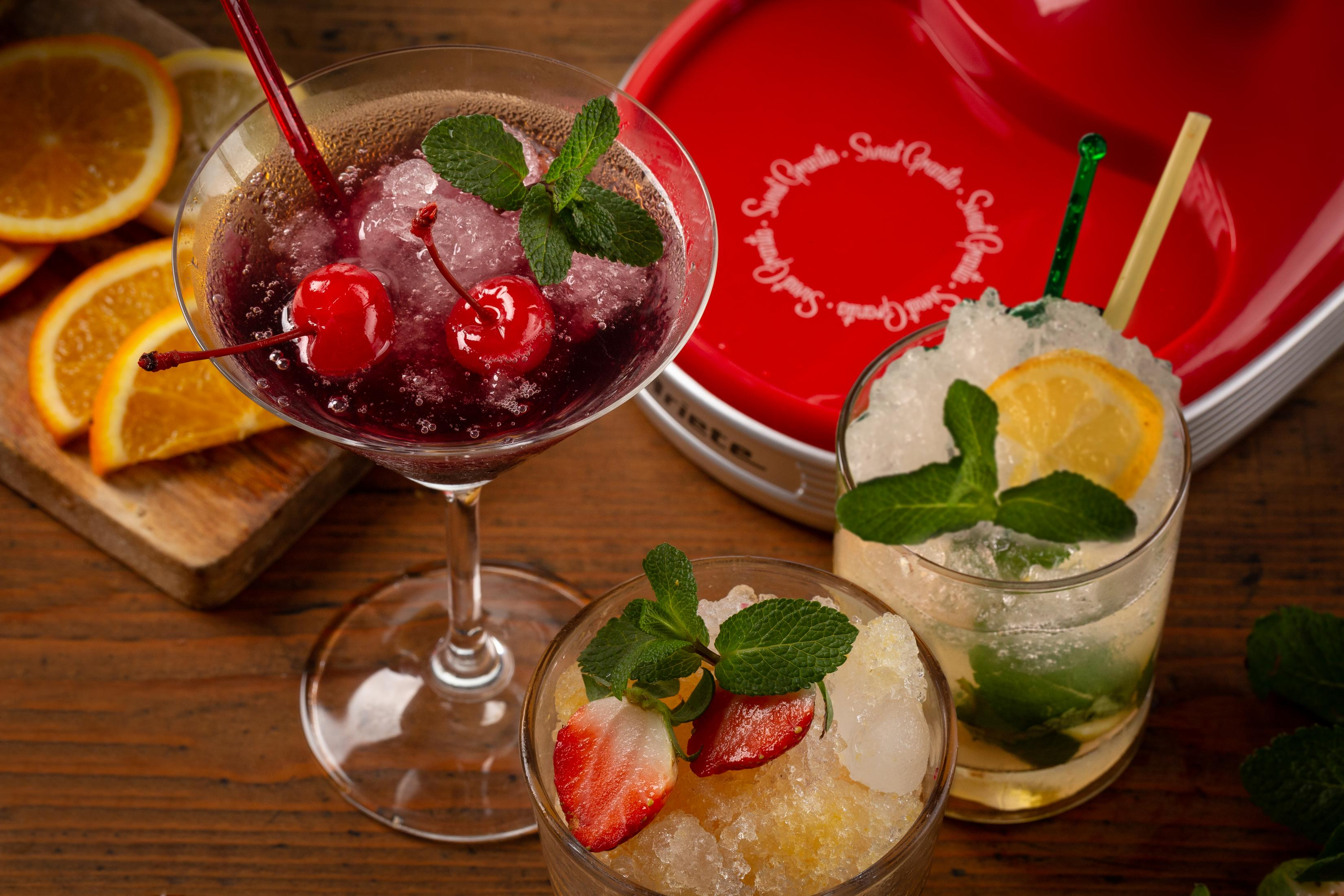 Tre cocktail con frutta e menta su tavolo di legno.