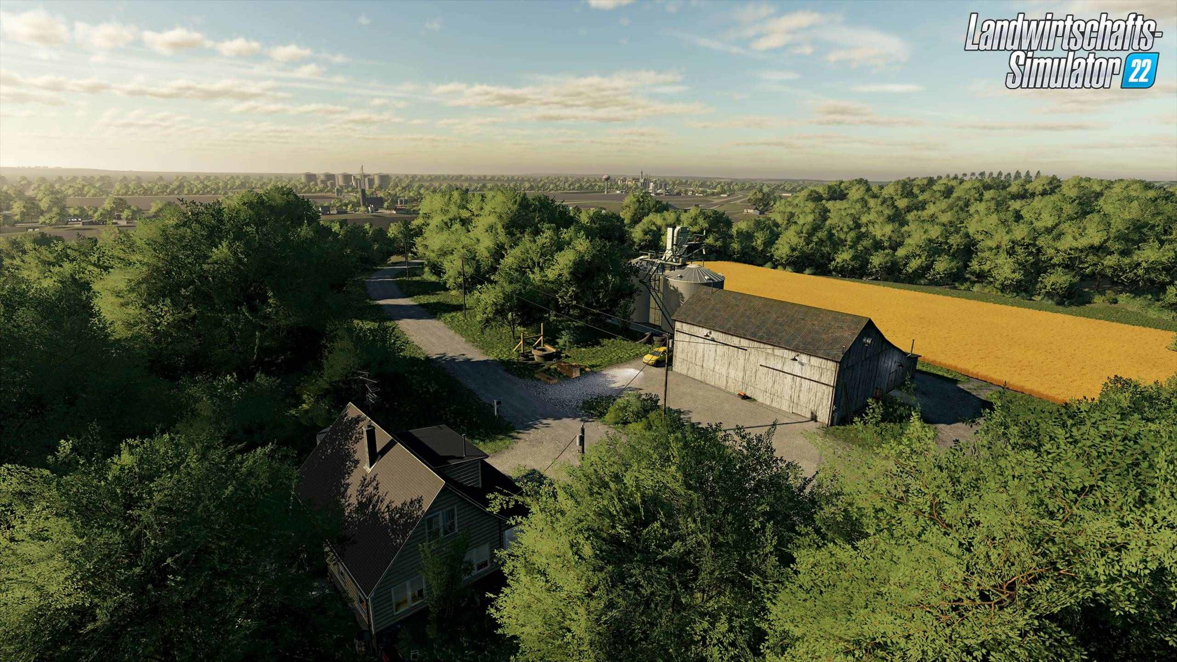 Ein Bauernhof mit Scheune, Silos, Haus und goldenem Feld, umgeben von grünen Bäumen.