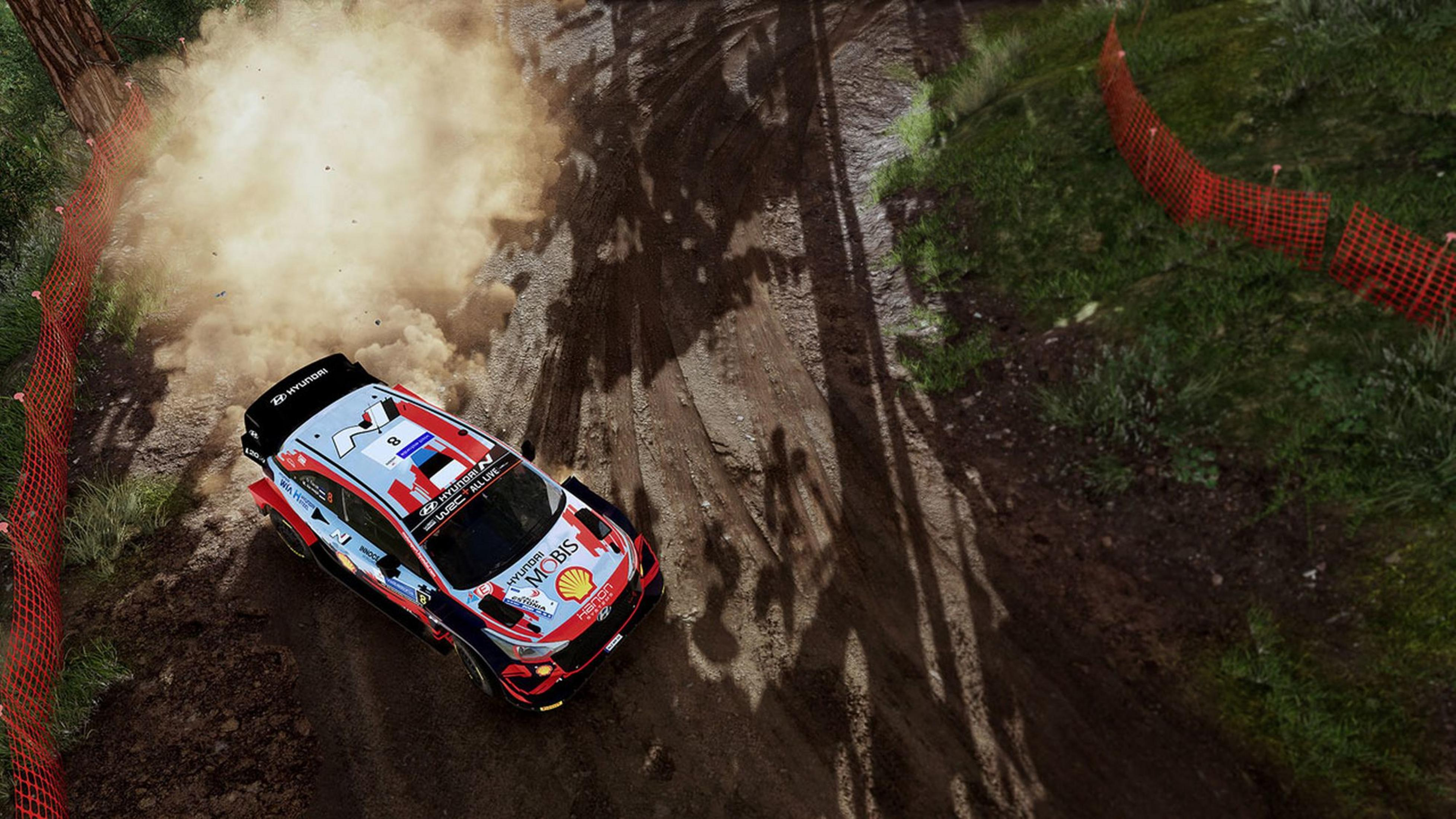 Ein Rallyeauto fährt auf einer Schotterstrecke, wirbelt Staub auf.