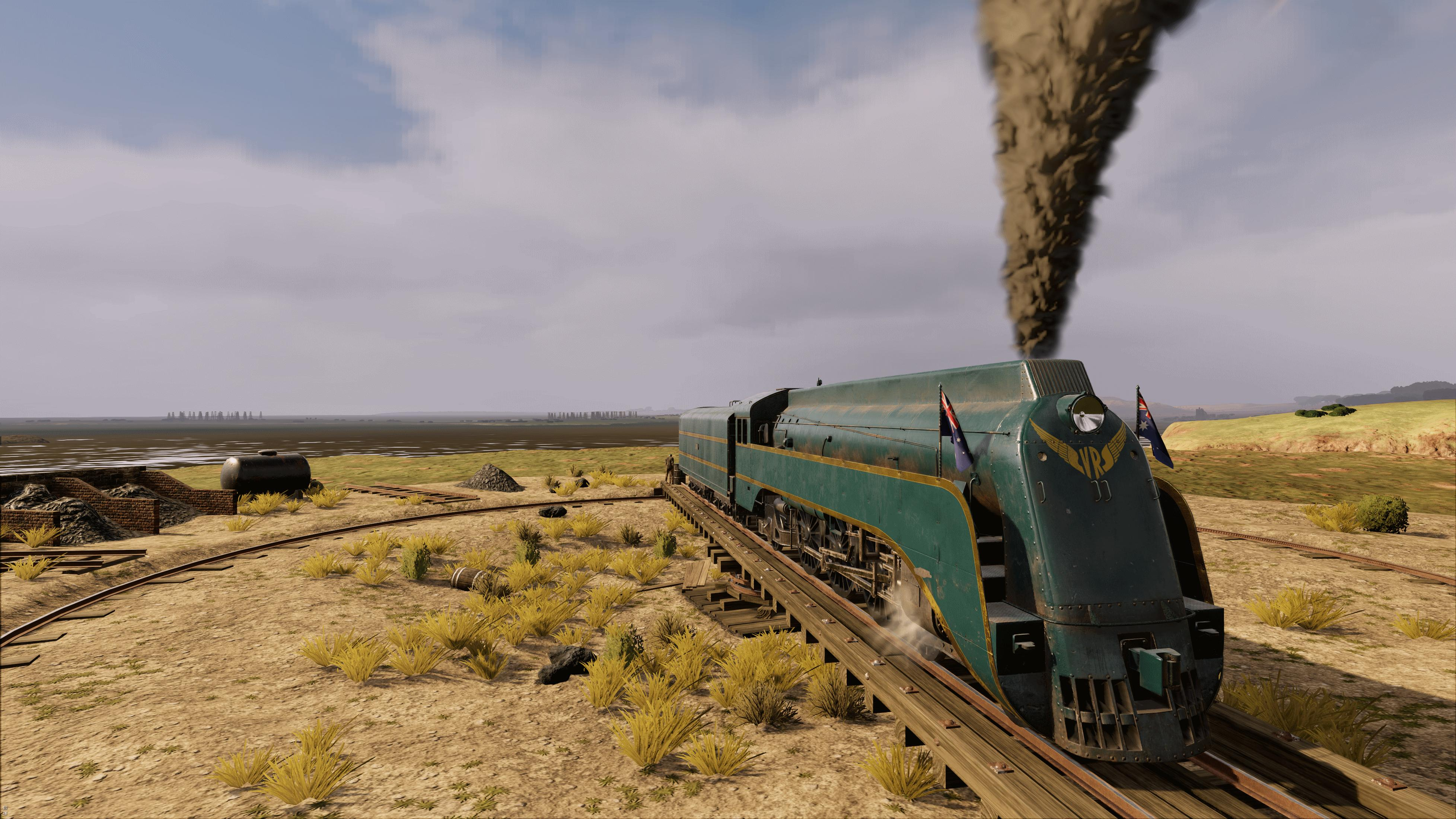 Eine grüne Dampflokomotive mit australischer Flagge fährt auf einem Gleis.