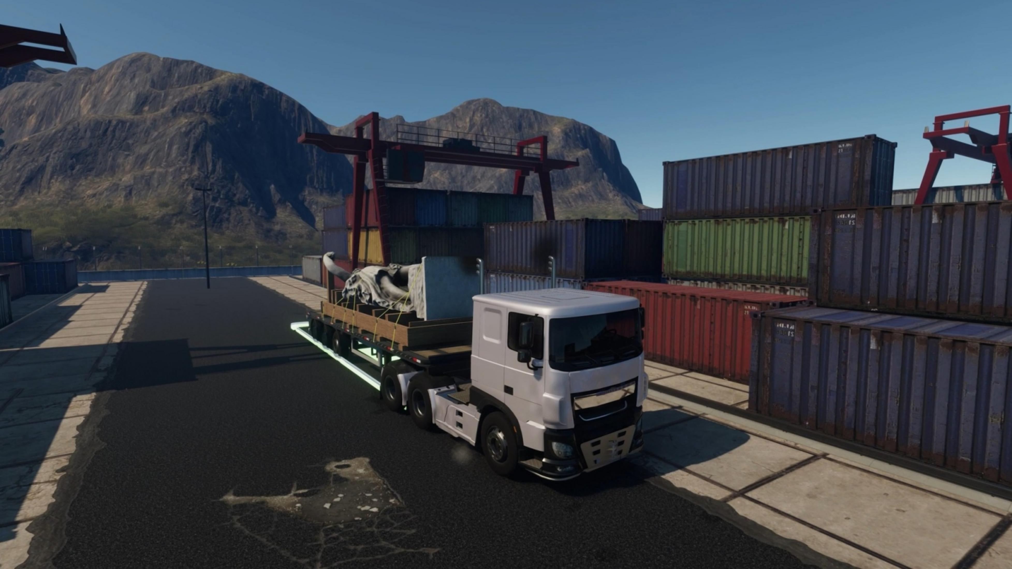 Ein weißer LKW mit einer Ladung auf einem Tieflader im Containerhafen.