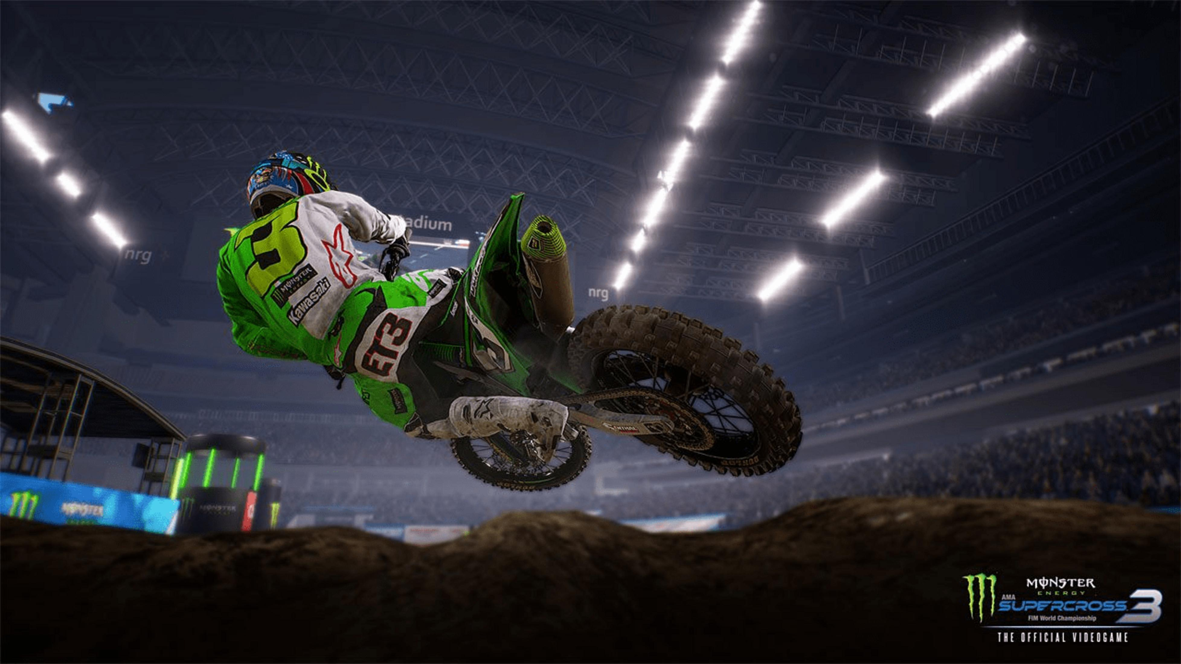 Ein Motocross-Fahrer in Grün springt in einer Arena.