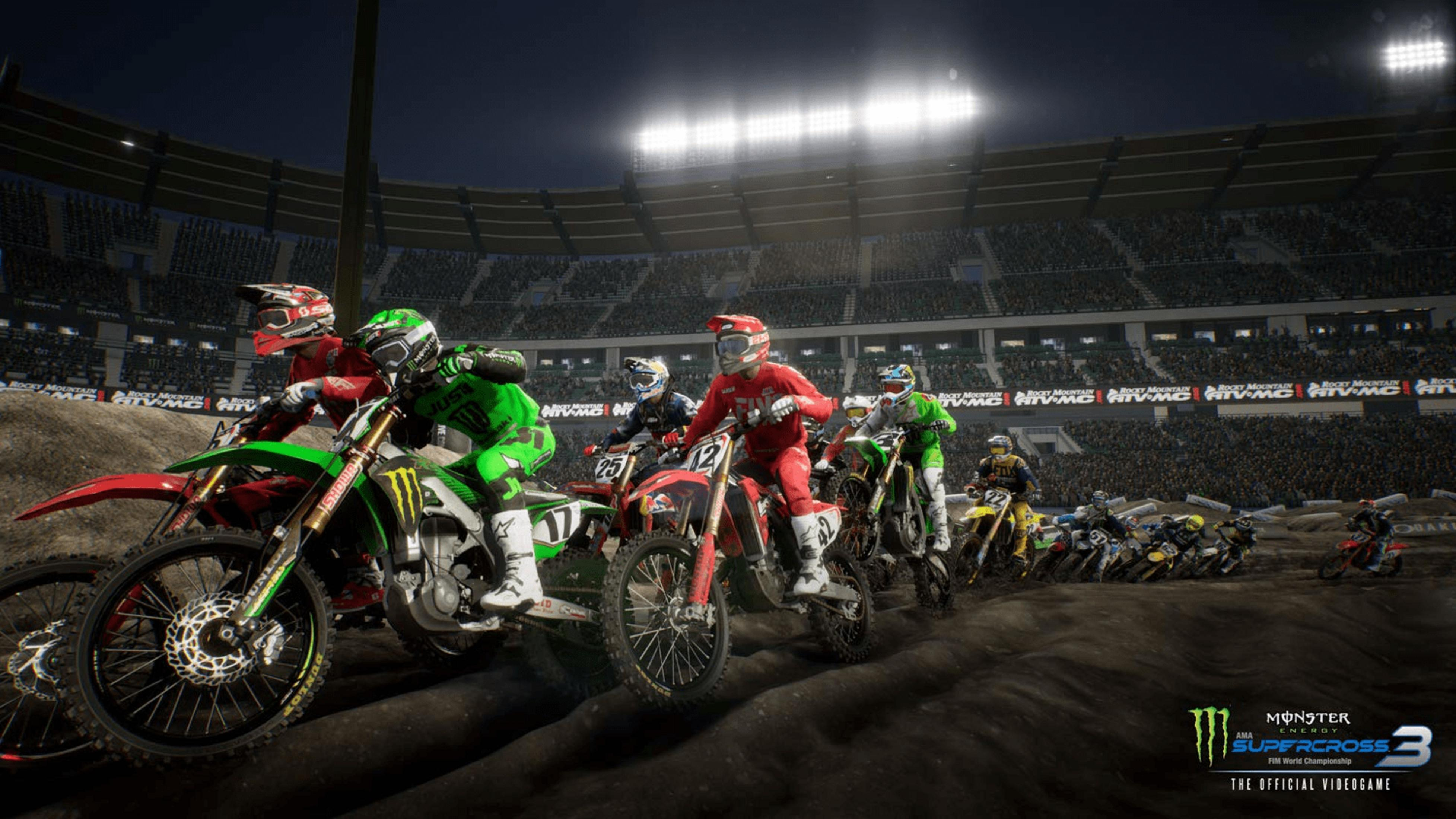 Motorradrennfahrer in bunten Anzügen fahren auf einer schlammigen Strecke in einem Stadion.