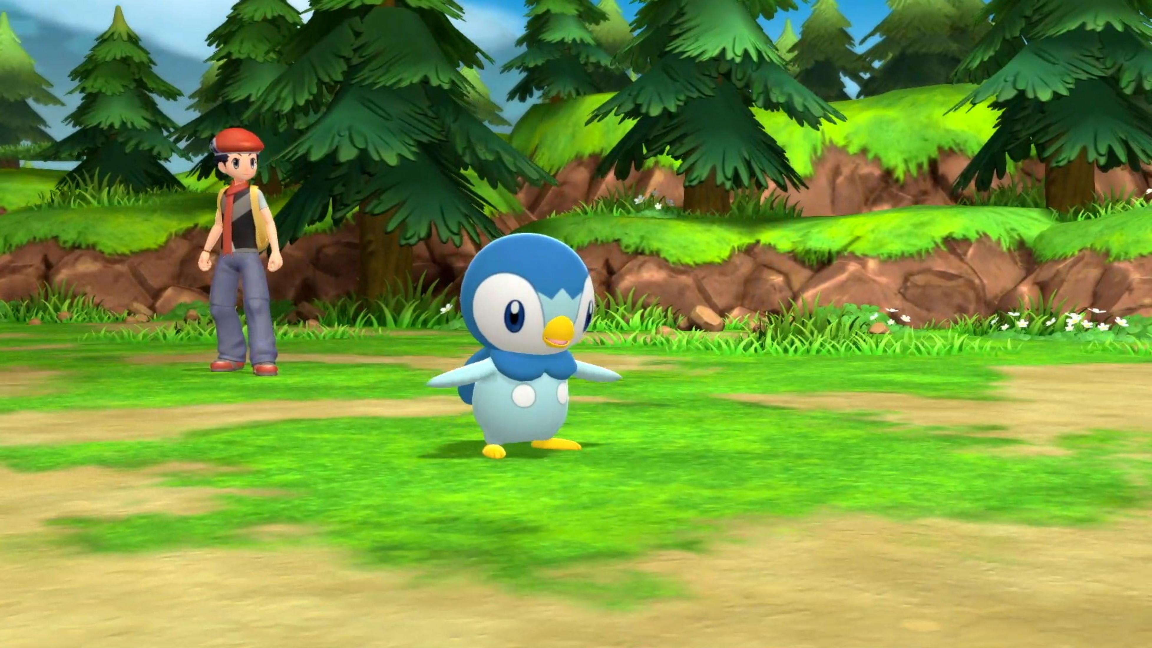 Eine blaue pinguinähnliche Kreatur steht auf Gras, dahinter ein Junge mit roter Mütze.