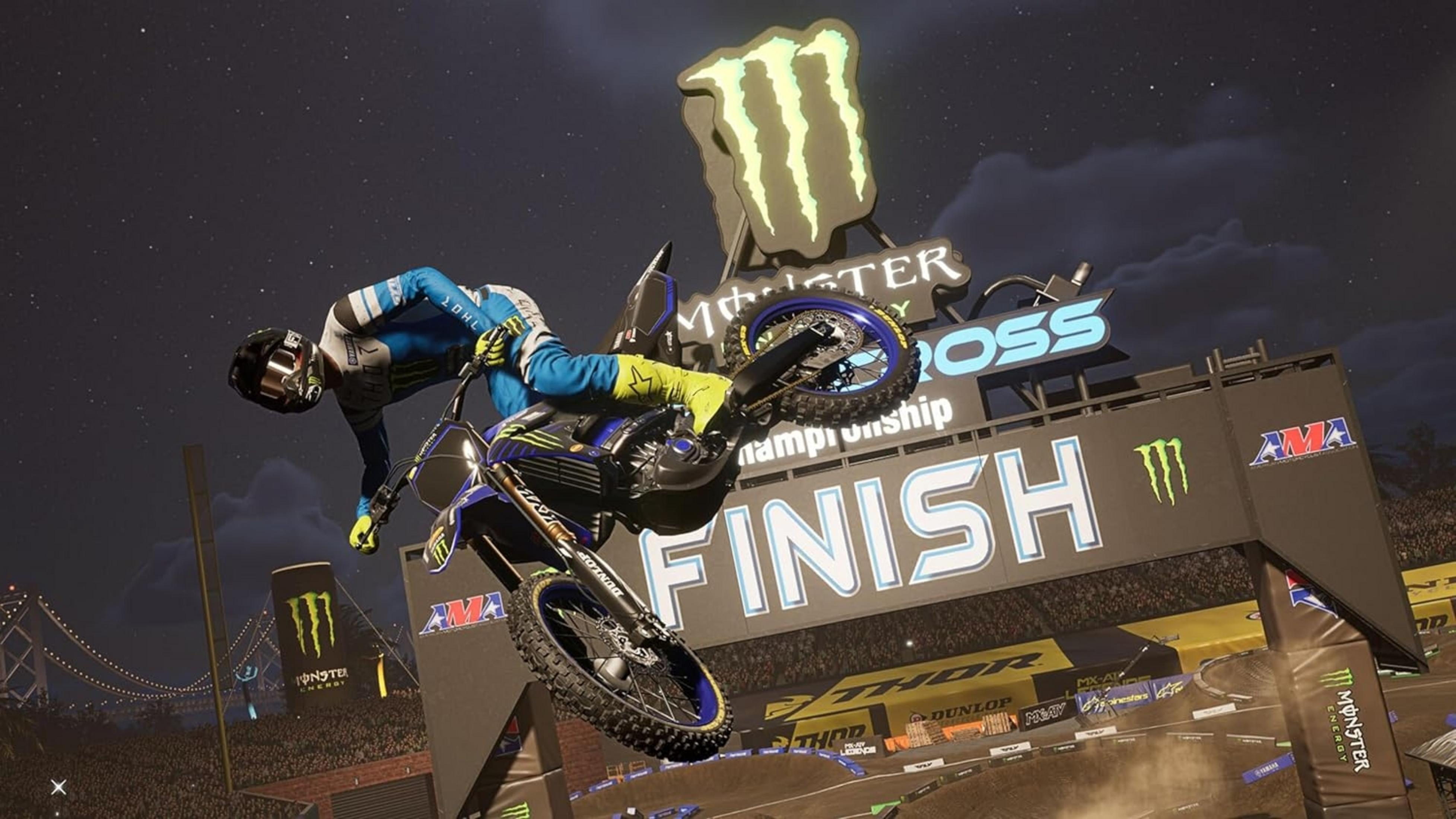 Ein Motorradfahrer springt bei Nacht über eine Ziellinie, Monster Energy sponsert.